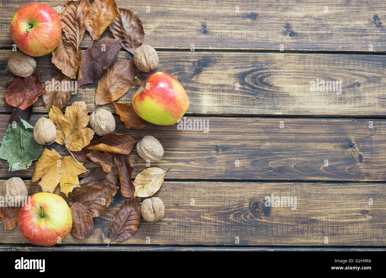Asciugare le foglie di autunno, le mele e i dadi sul tavolo di legno Foto Stock