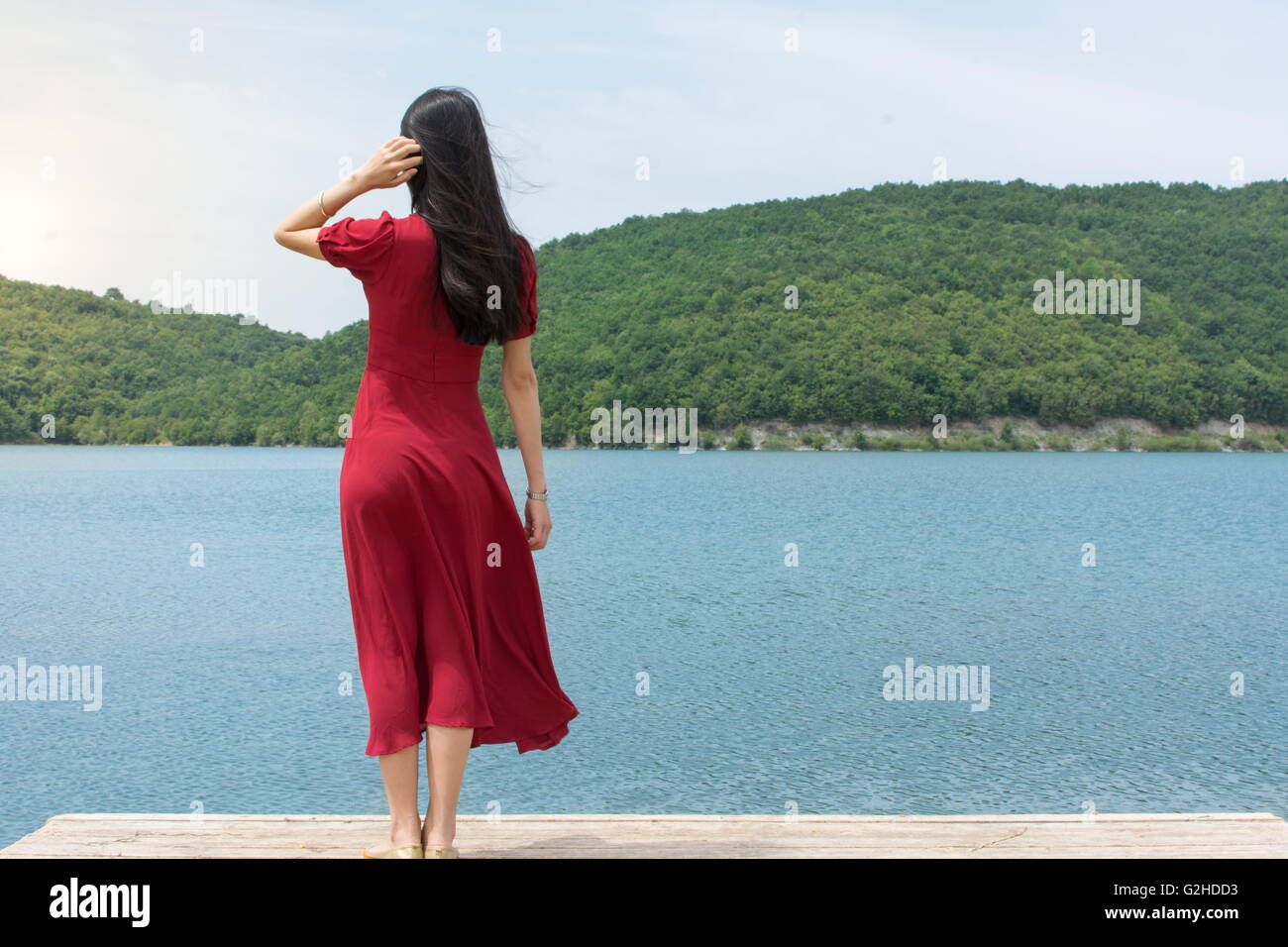 Moda donna in piedi di fronte ad un lago da soli Foto Stock