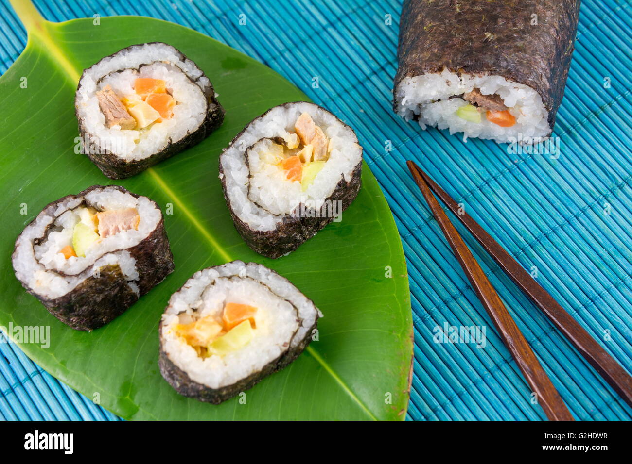 Rotoli di sushi servita su una foglia con bacchette di legno Foto Stock