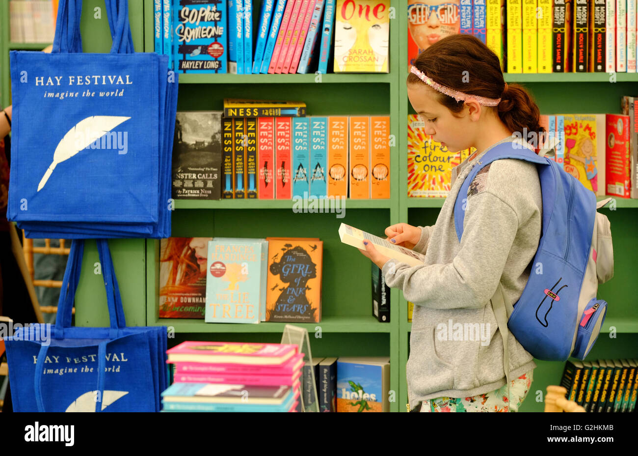 Festival di fieno, Wales, Regno Unito - Maggio 2016 - una giovane ragazza sceglie un libro nella sezione per bambini del Festival Bookshop il giorno 6 di evento di quest'anno. Foto Stock