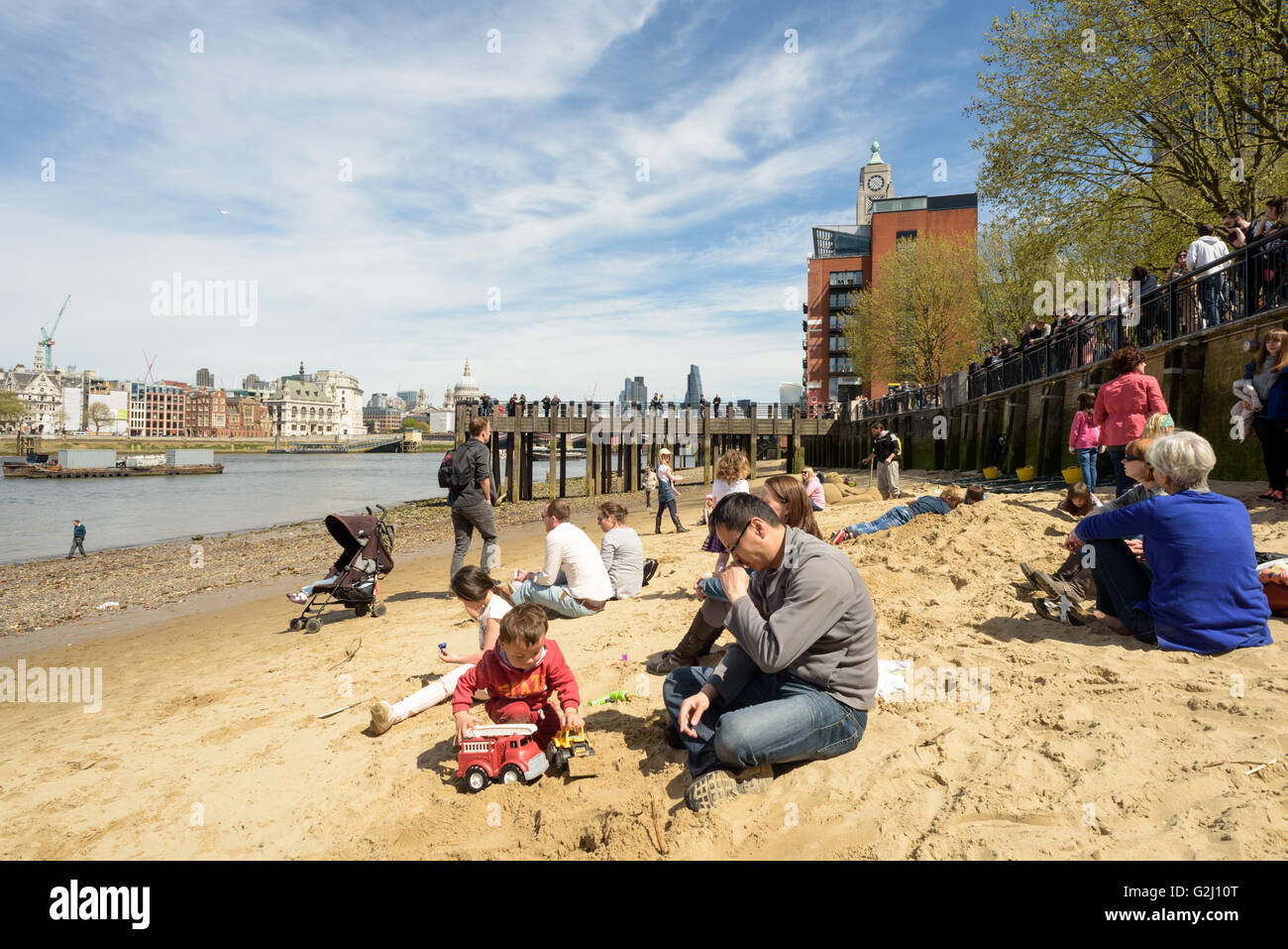 Seduta di famiglia e rilassante sulle rive sabbiose del Fiume Tamigi a Londra con la bassa marea nel maggio sunshine 2016 Foto Stock