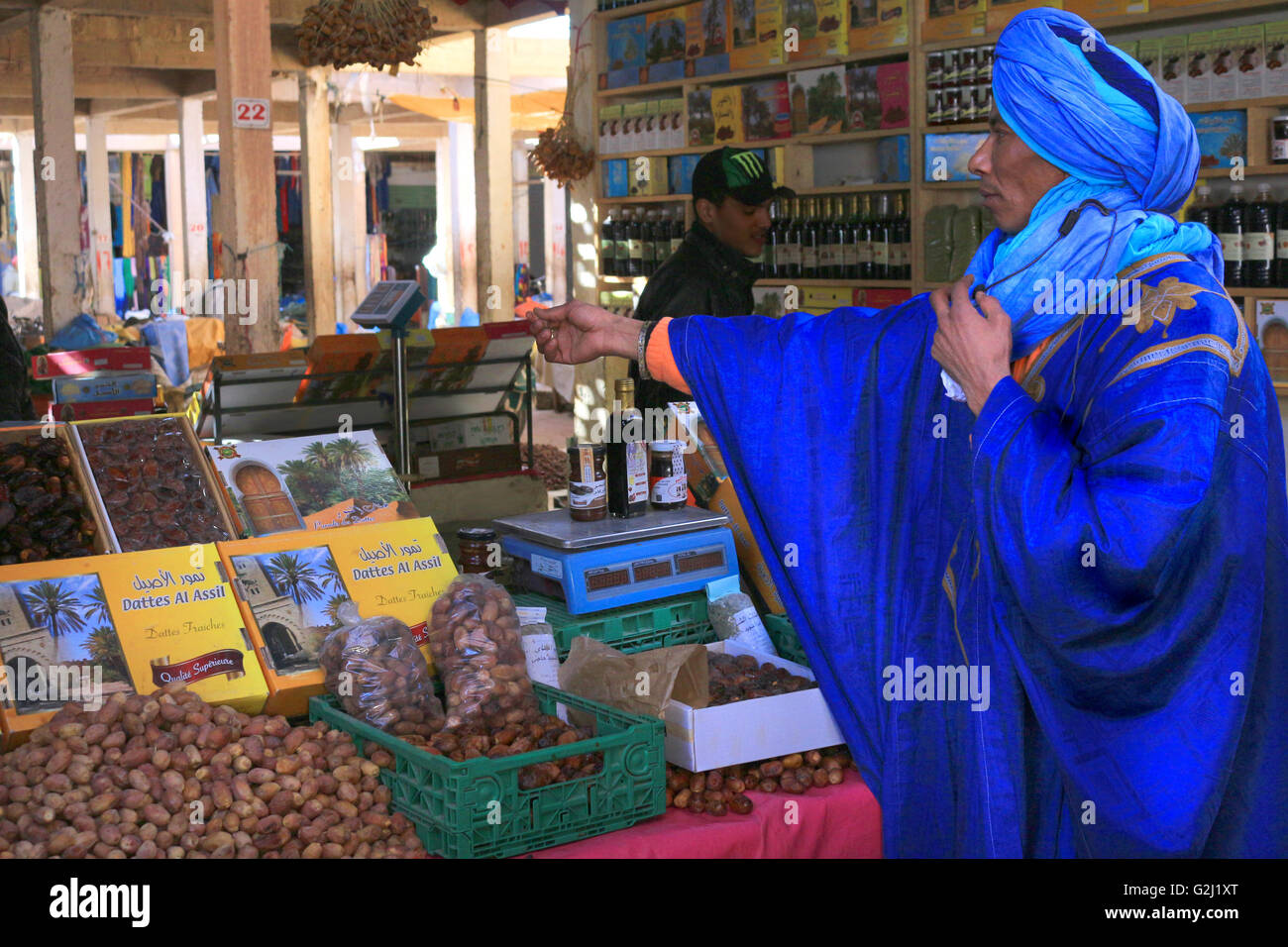 RISSANI, Marocco, febbraio 22, 2016: tradizionali Berbere uomo vestito nel tradizionale blu Tuareg abbigliamento di effettuare un acquisto in Ri Foto Stock
