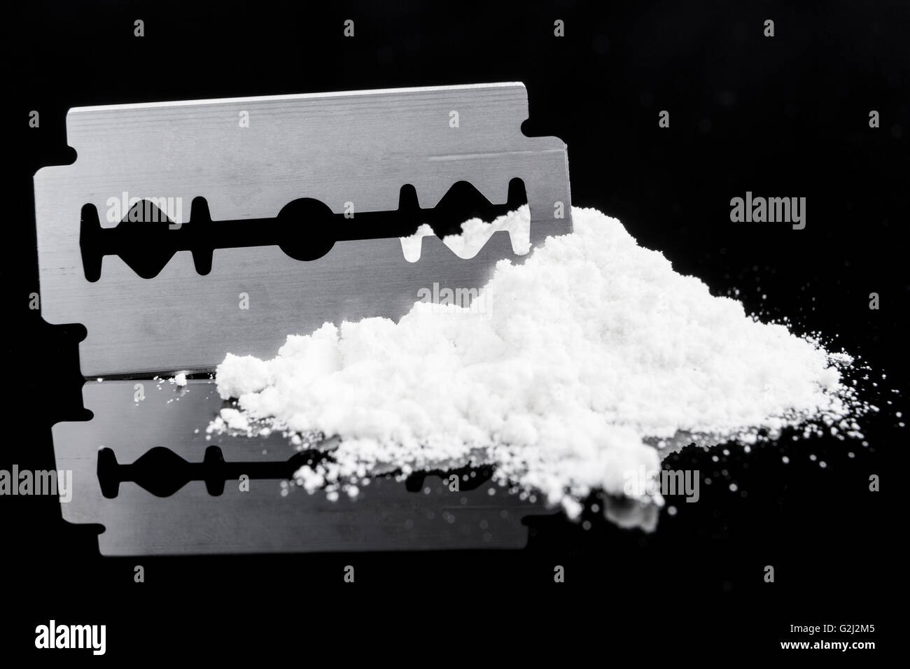 Una lama di rasoio closeup sulla polvere del farmaco su sfondo nero con la riflessione Foto Stock