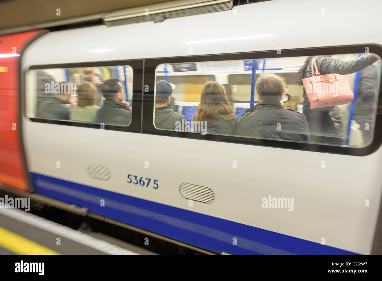 La gente seduta su una Londra metropolitana treno in viaggio verso le loro destinazioni con movimento sfocata del treno in azione Foto Stock