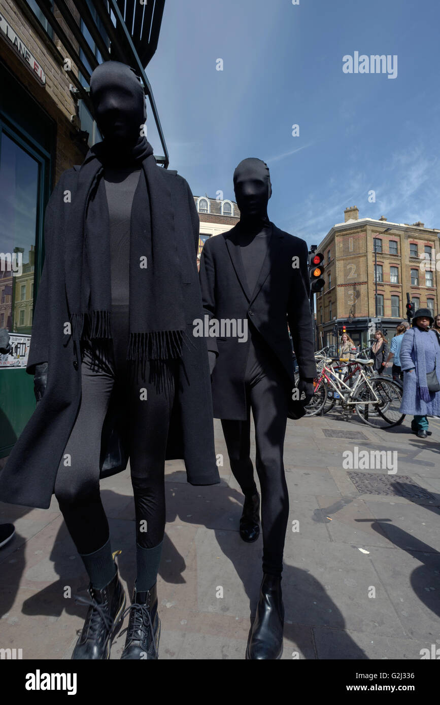 Due uomini totalmente vestita di nero tute e maschere a piedi su Brick Lane a Londra Può Giorno 1Holiday Foto Stock