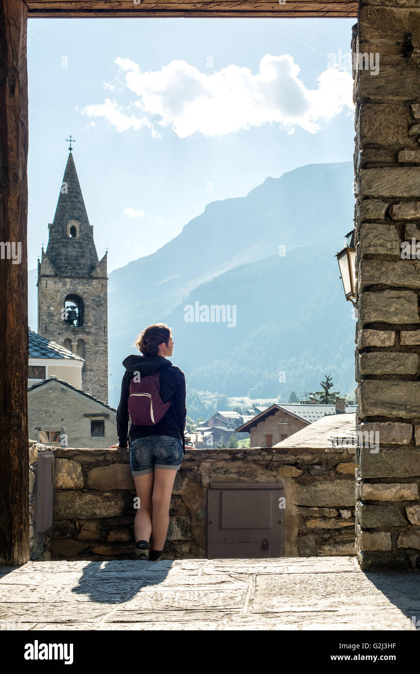 Giovane donna adulta guardando alla vista panoramica dal villaggio, vista posteriore, Lanslevillard, Val Cenis Vanoise, Francia Foto Stock