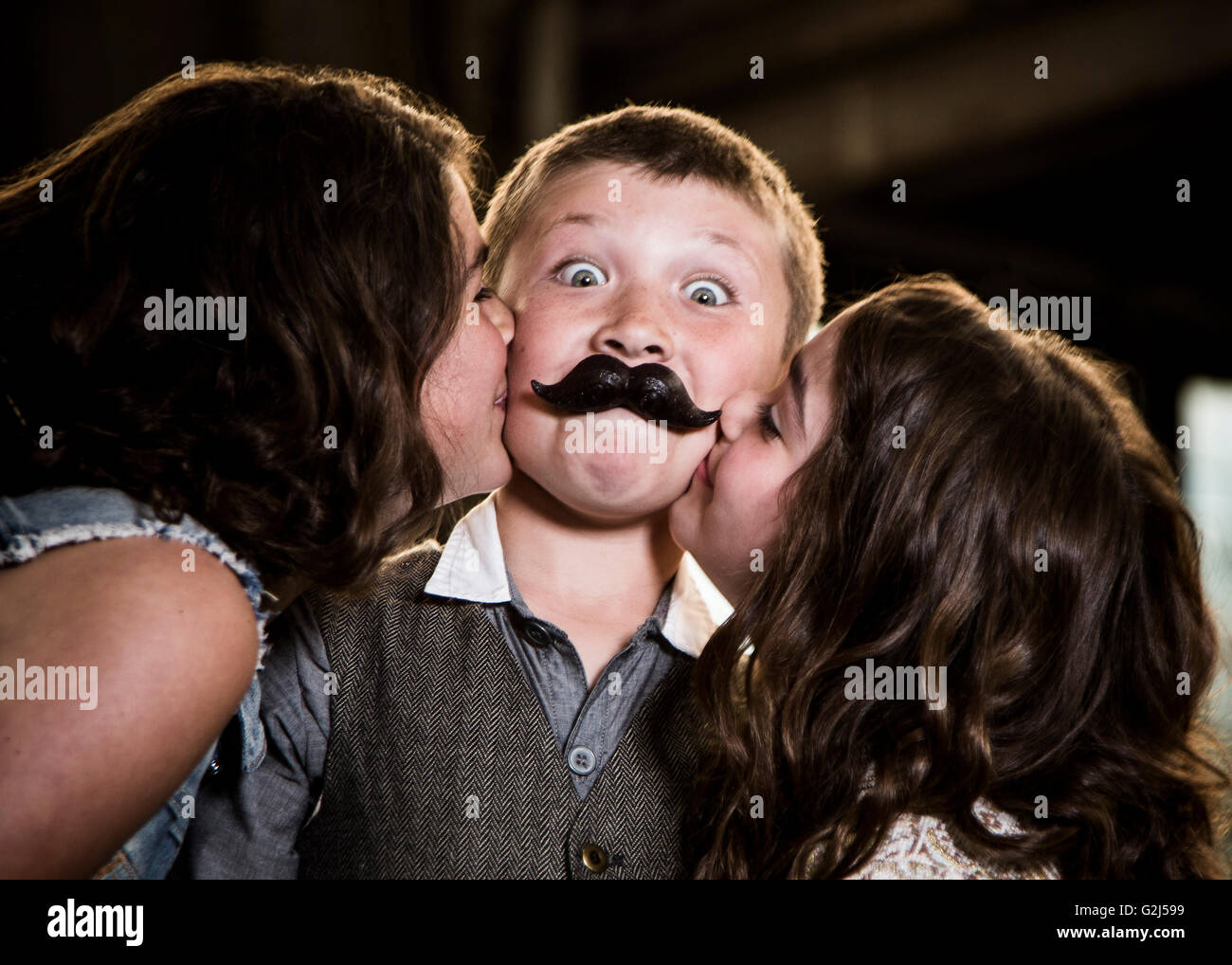 Due ragazze baciare Ragazzo con labbra di cera in magazzino abbandonato Foto Stock