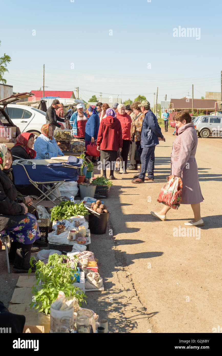 La gente cerca di produrre e di ortaggi per la vendita su un mercato locale fiera in Russia Foto Stock