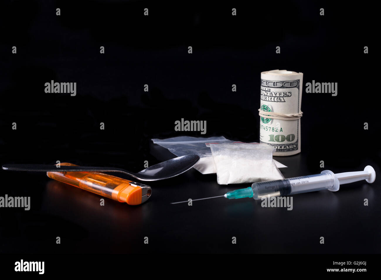 Farmaci con un cucchiaio di siringa e un accendino accanto a un sacco di dollari su sfondo nero Foto Stock