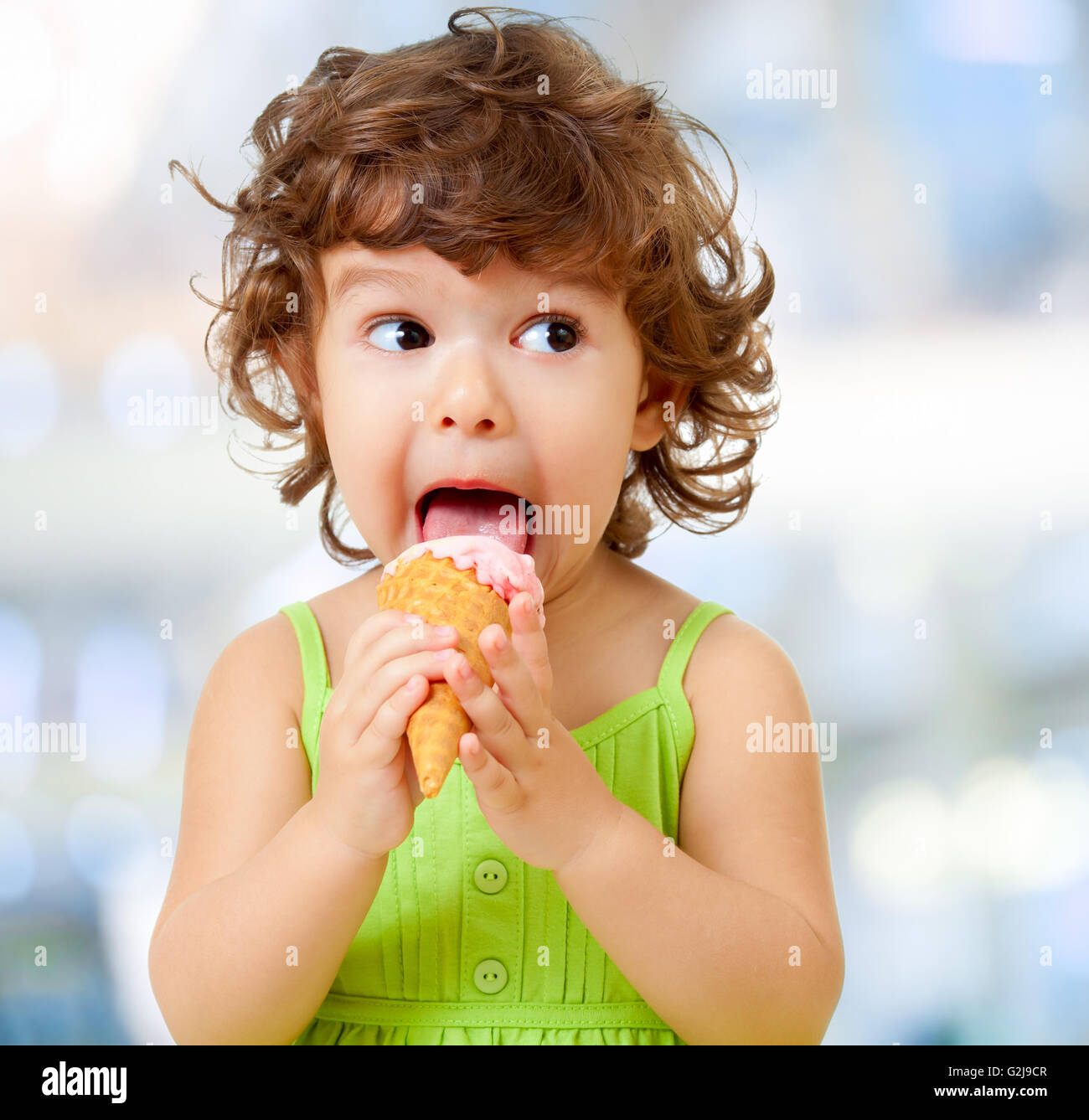 Funy kid mangiare gelato su sfondo sfocato. Foto Stock