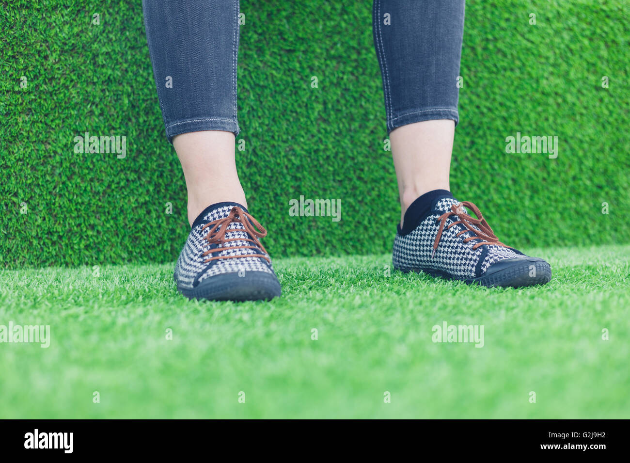Le gambe e i piedi di una giovane donna in appoggio su alcuni astro turf Foto Stock