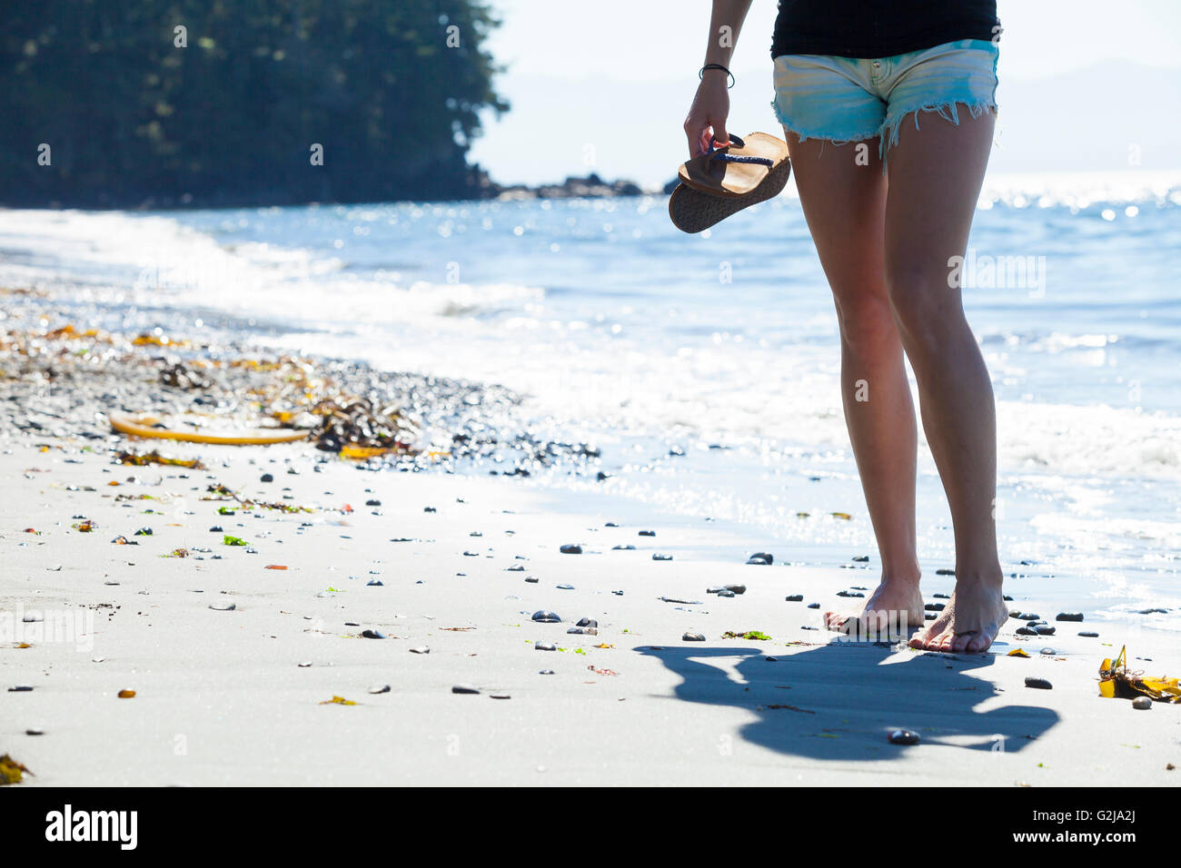 Una giovane donna si erge a piedi nudi sulla sabbia in spiaggia francese Parco Provinciale. Isola di Vancouver, BC, Canada. Foto Stock