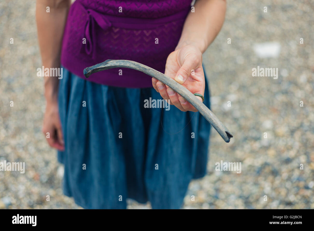 Una giovane donna è in piedi su un fiume di ghiaia banca con un osso che ha ritrovato la pettinatura di spiaggia Foto Stock