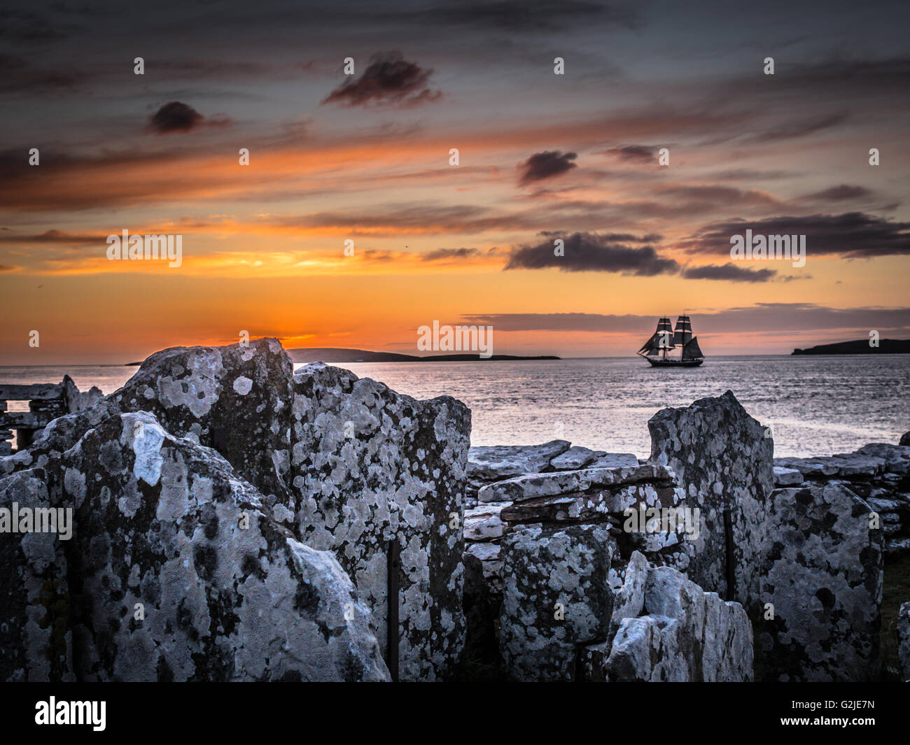 Square truccate tall ship Morgenster lascia Orkney al tramonto tra Eynhallow isola e terraferma, visto dal Broch di Gurness Foto Stock