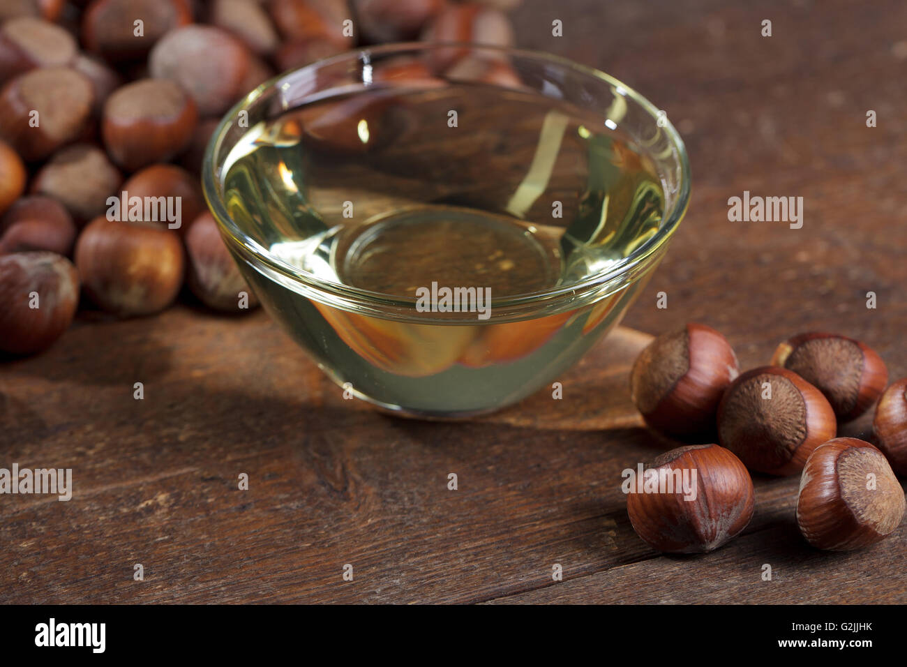 Piccola ciotola di vetro con olio di nocciola e un paio di nocciole intere Foto Stock