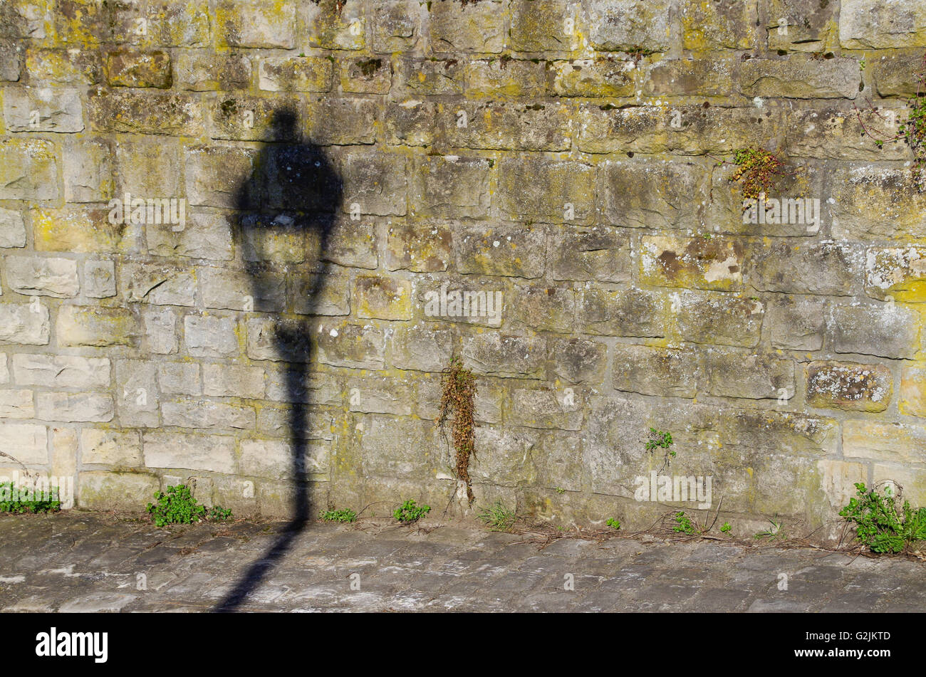 Ombra di una lanterna di strada su un muro di pietra nella città di Lussemburgo Foto Stock