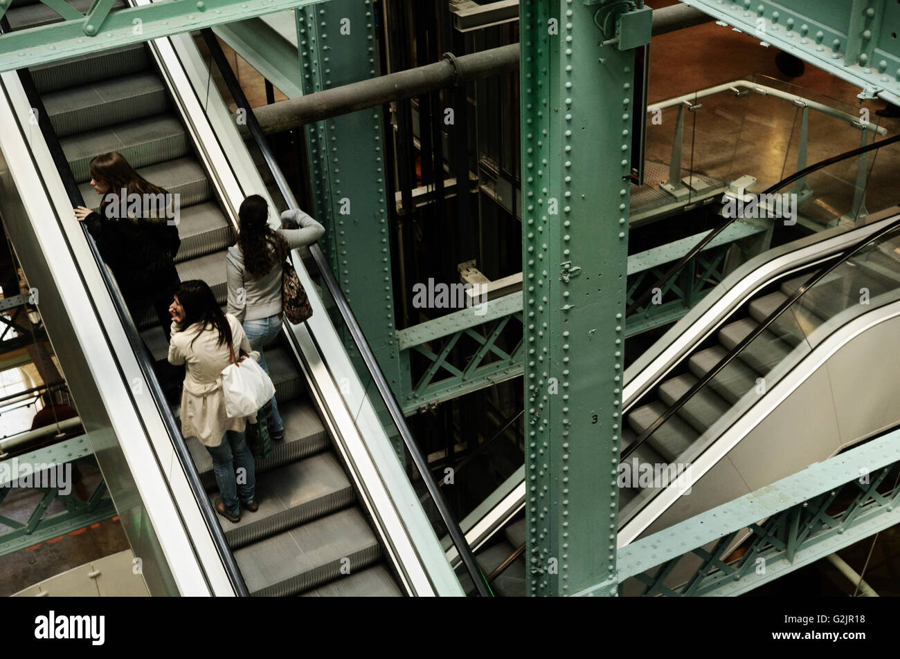 Tre giovani donne in piedi su una scala mobile all'interno del Guinness Storehouse, Dublino, Irlanda Foto Stock