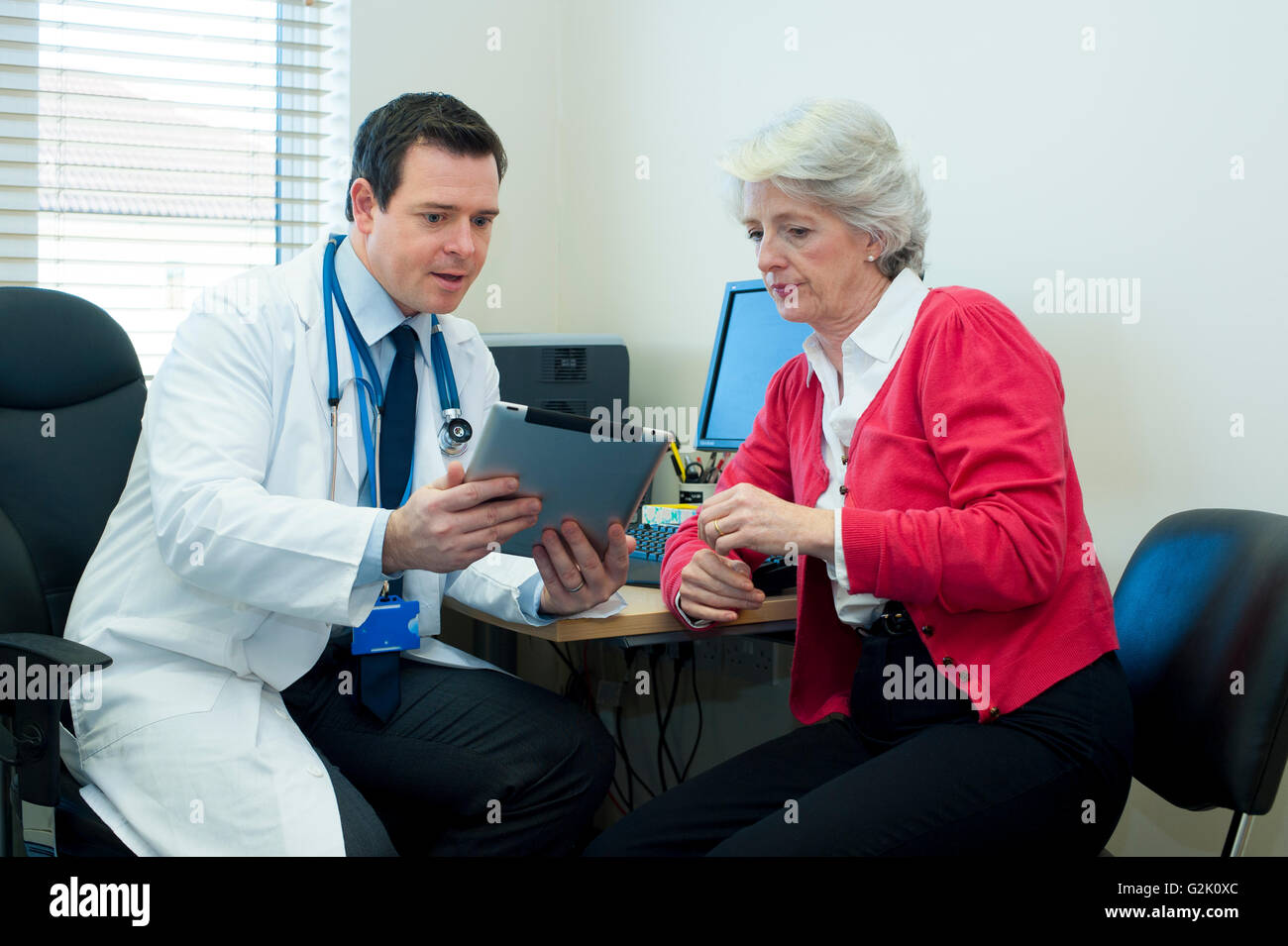 Medico discute le informazioni su un tablet con paziente femmina Foto Stock