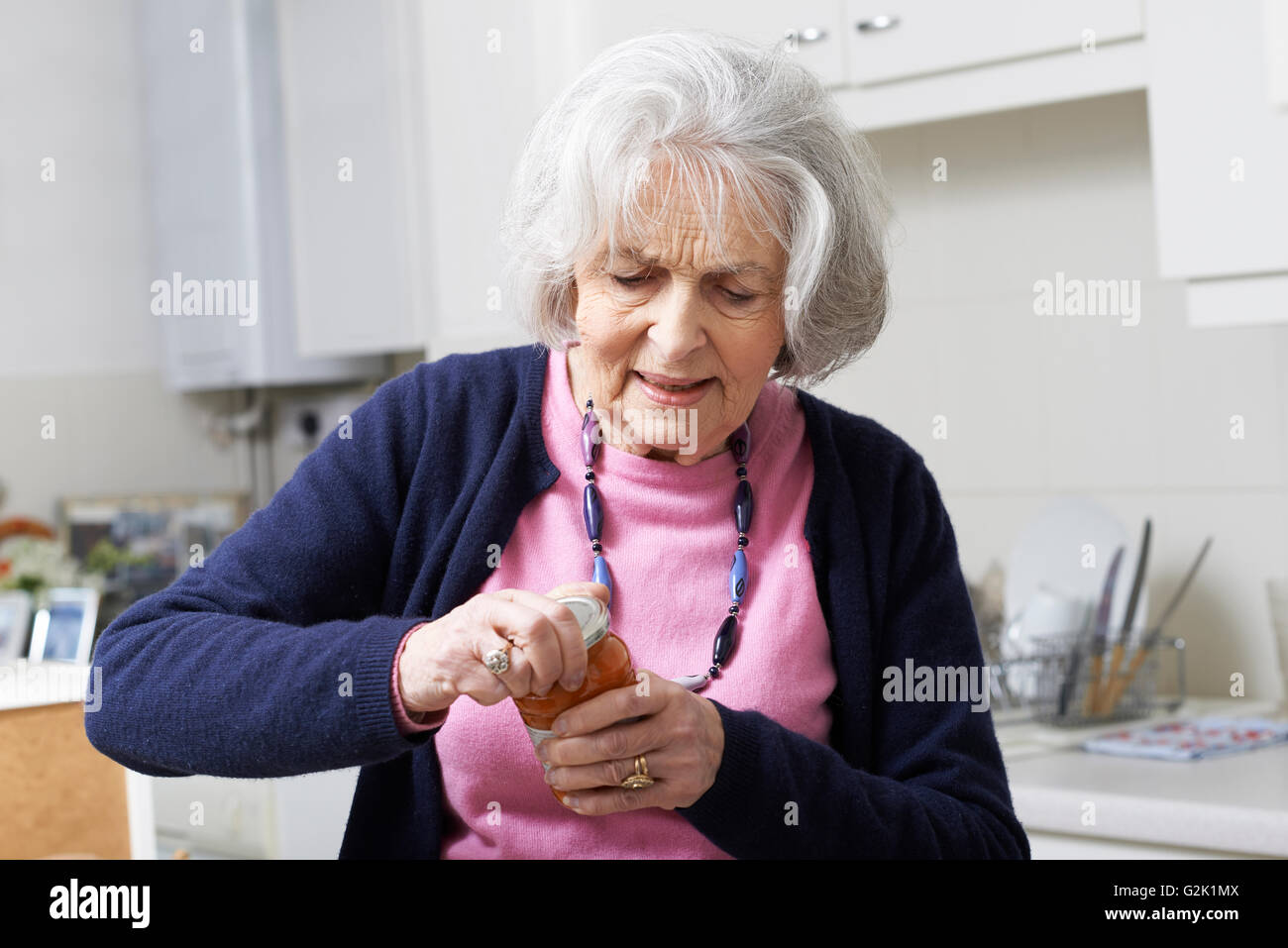 Senior donna lottando per portare il coperchio Jar Foto Stock