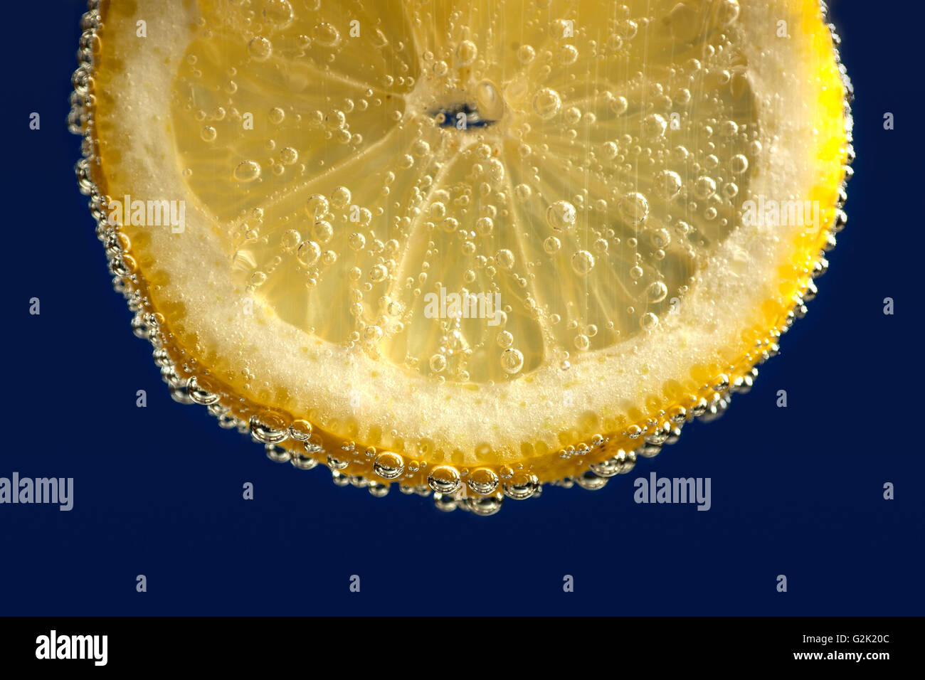 Fettina di limone in bolla bere su sfondo blu Foto Stock