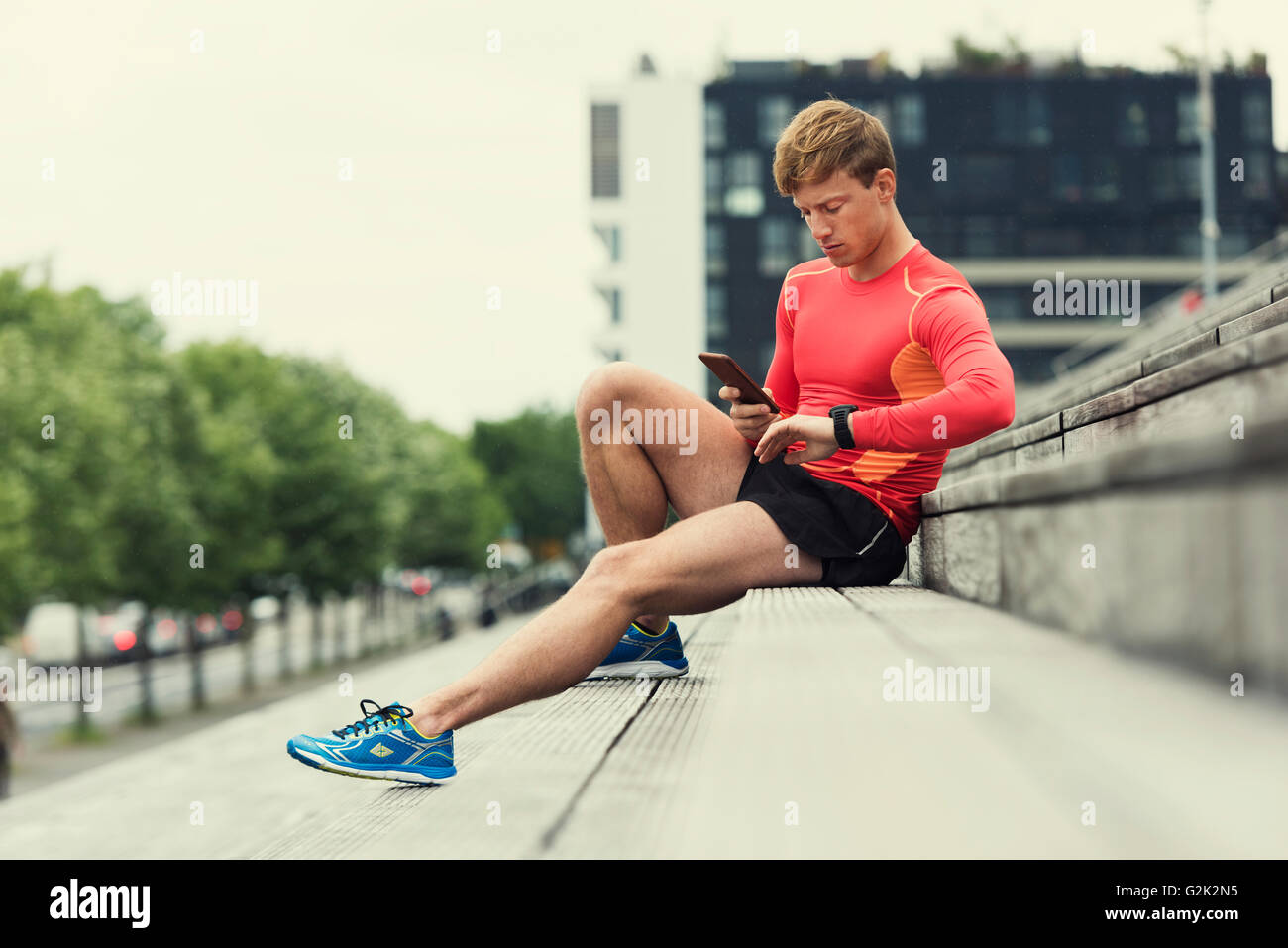 Controllo del pareggiatore sport performance sul suo telefono mobile e smartwatch app. Background urbano Foto Stock