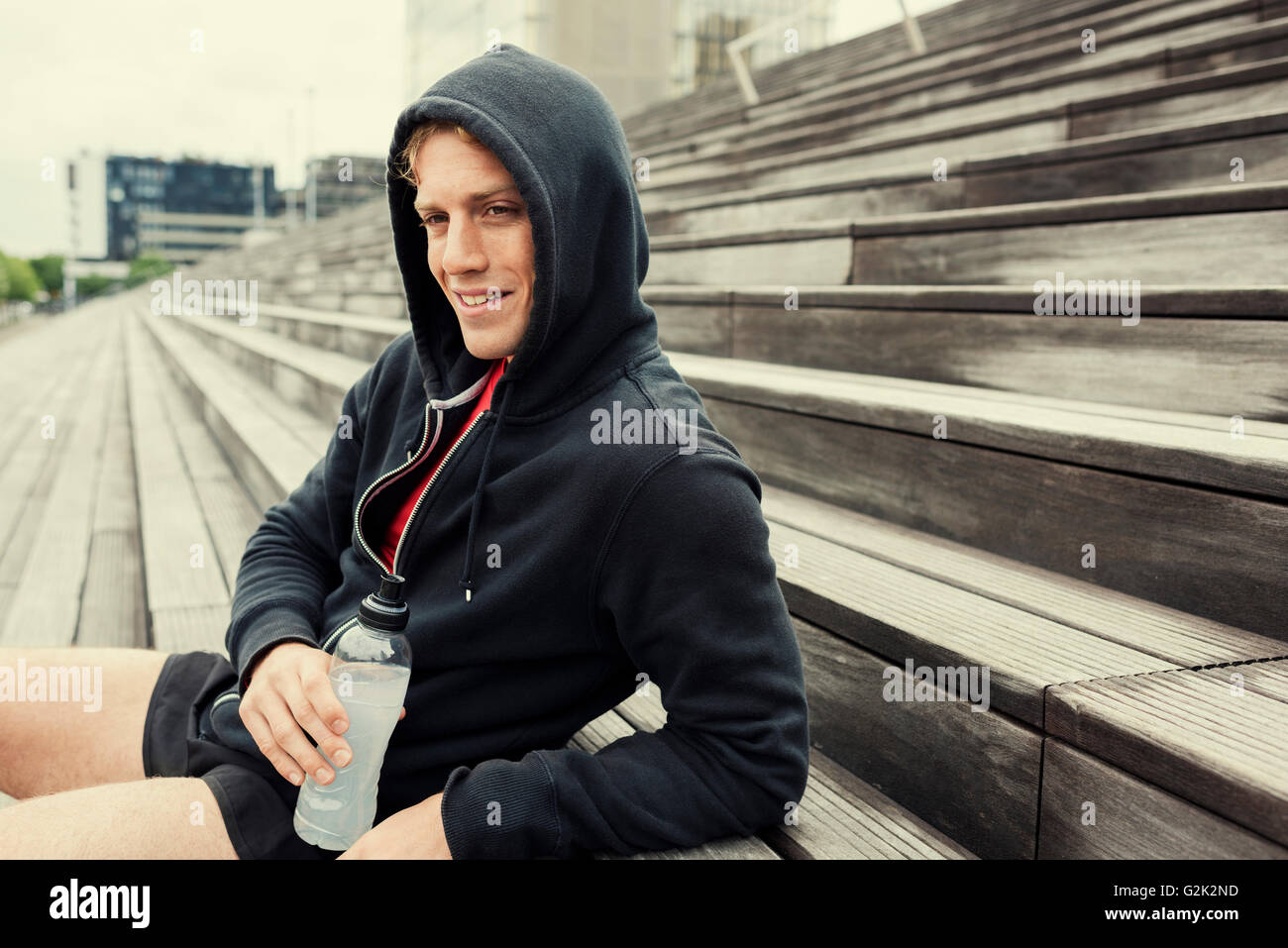 Urban sportman riposo dopo la sessione di allenamento seduta sulle scale. Acqua potabile Foto Stock