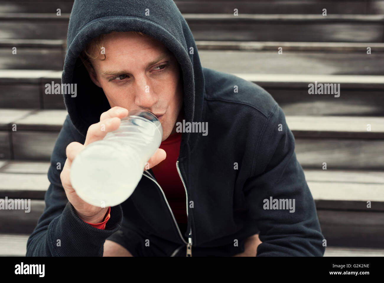 Urban sportman riposo dopo la sessione di allenamento seduta sulle scale. Acqua potabile Foto Stock