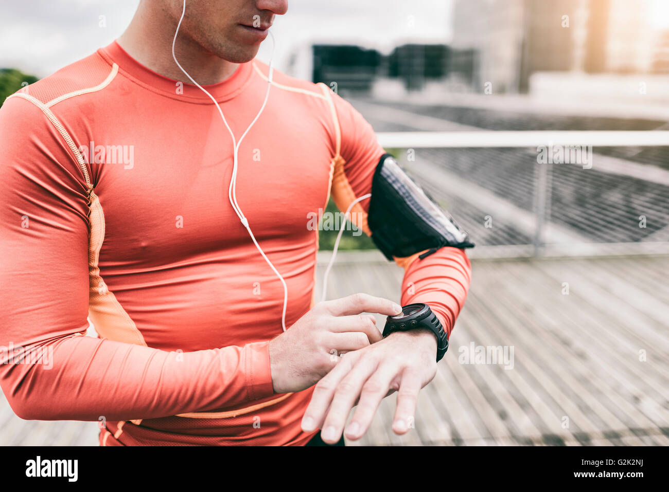 Urban runner uomo cercando app su sportwatch. Esecuzione maschio jogging smart guardare al di fuori Foto Stock