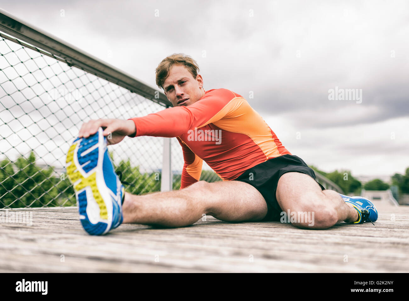 Sportman stretching fuori sul ponte di legno Foto Stock