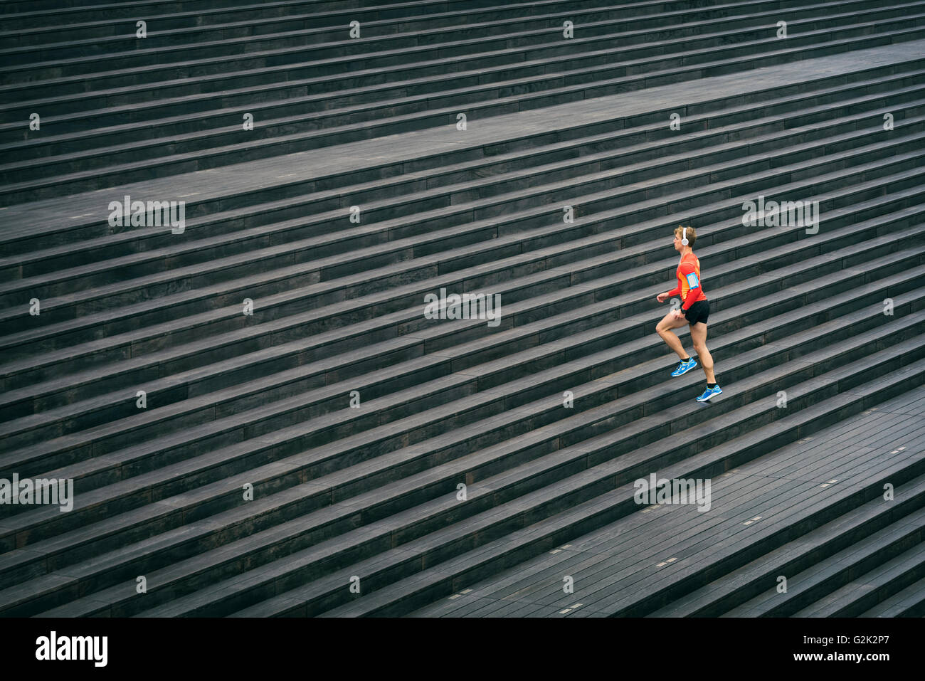 Esecuzione di atleta jogging all'aperto ascoltando la musica sul telefono cellulare. Sport al di fuori su scala in legno Foto Stock