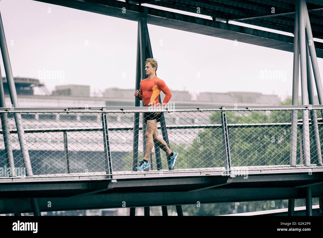 Maschio in esecuzione di jogging sul grafico il ponte di metallo Foto Stock