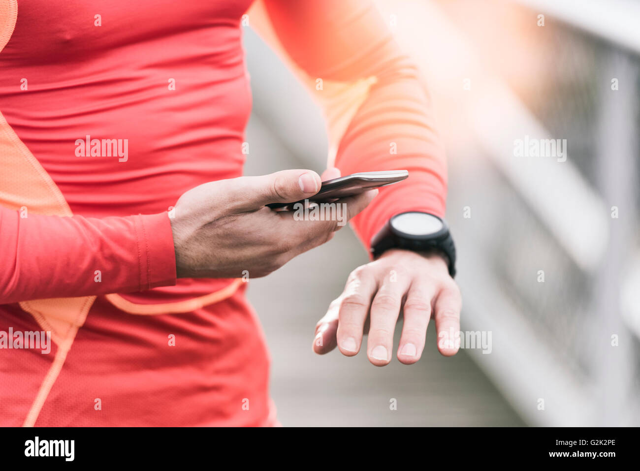 Uomo che corre controllando le prestazioni sportive sul suo telefono mobile e smartwatch app Foto Stock