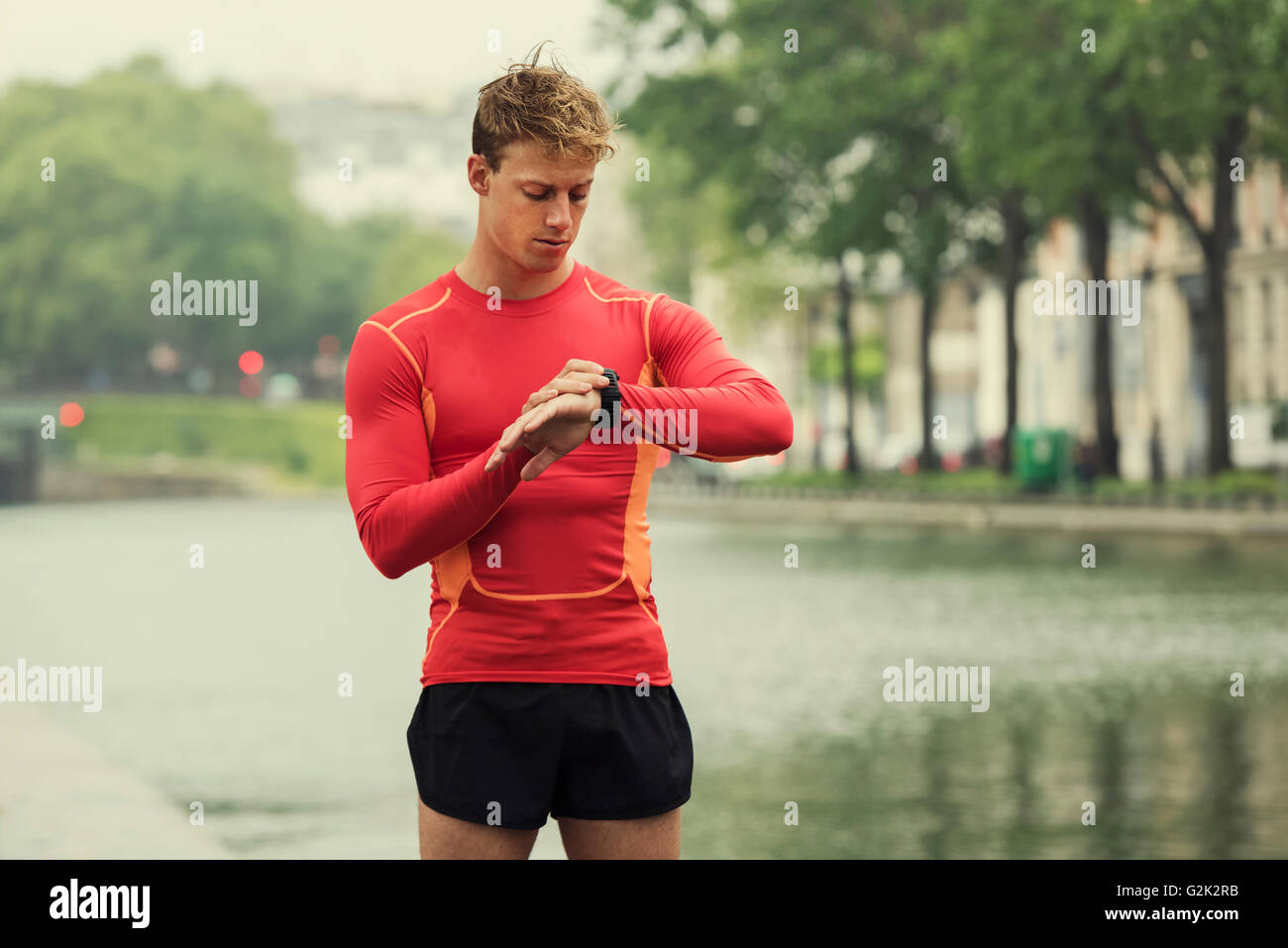 Giovane uomo che corre guardando al suo monitor frequenza cardiaca sport smart watch. Foto Stock