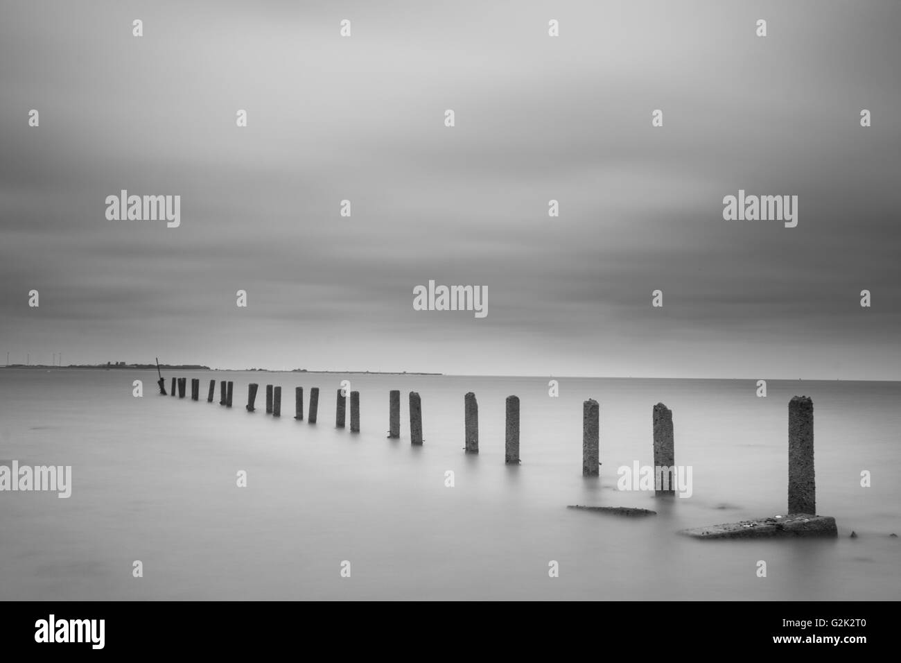 Chiave di alta immagine in bianco e nero del molo vecchio tralicci sulla spiaggia di Suffolk di Clackton. Foto Stock