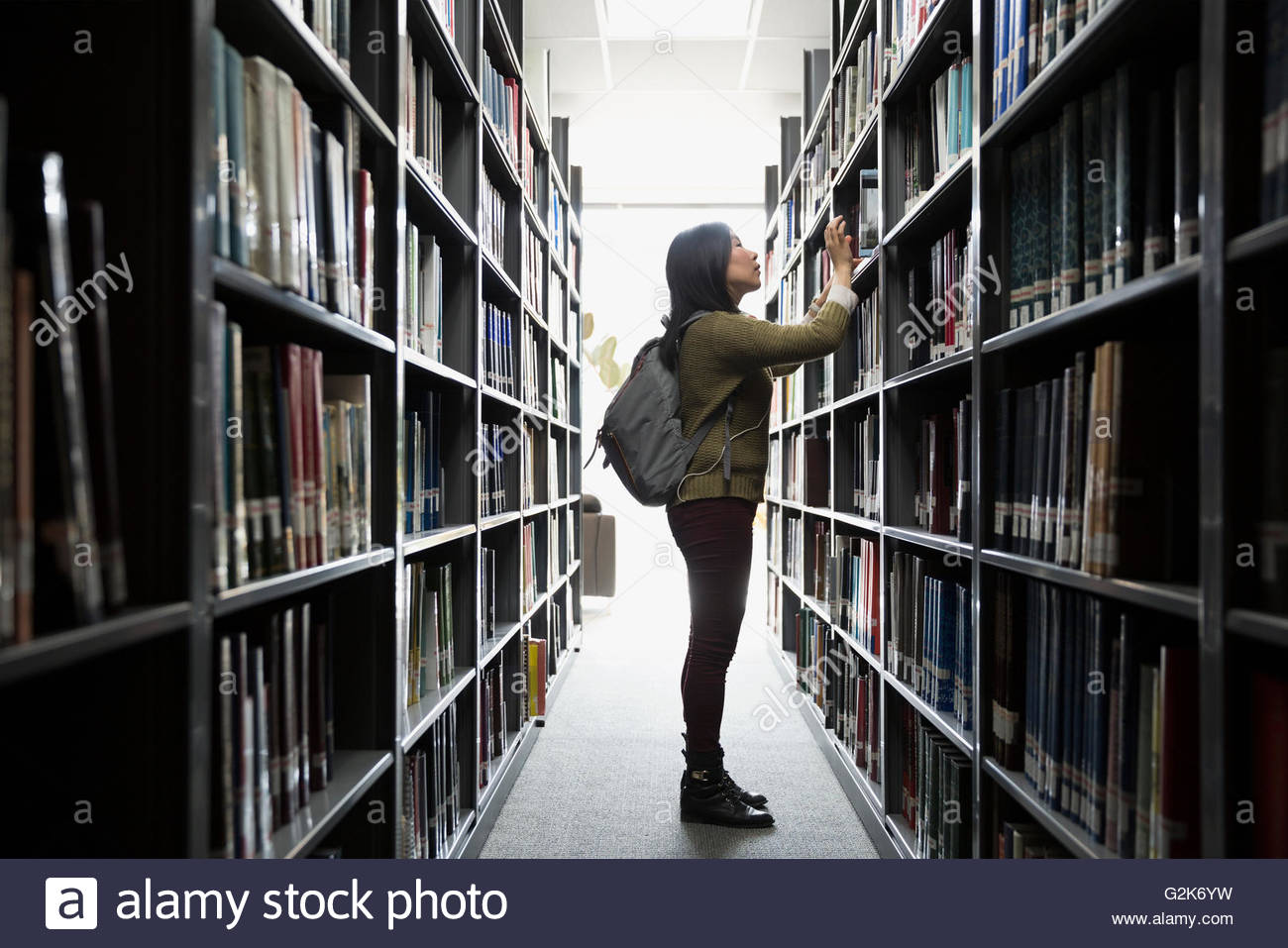 Studente di College alla ricerca di libro in biblioteca Foto Stock