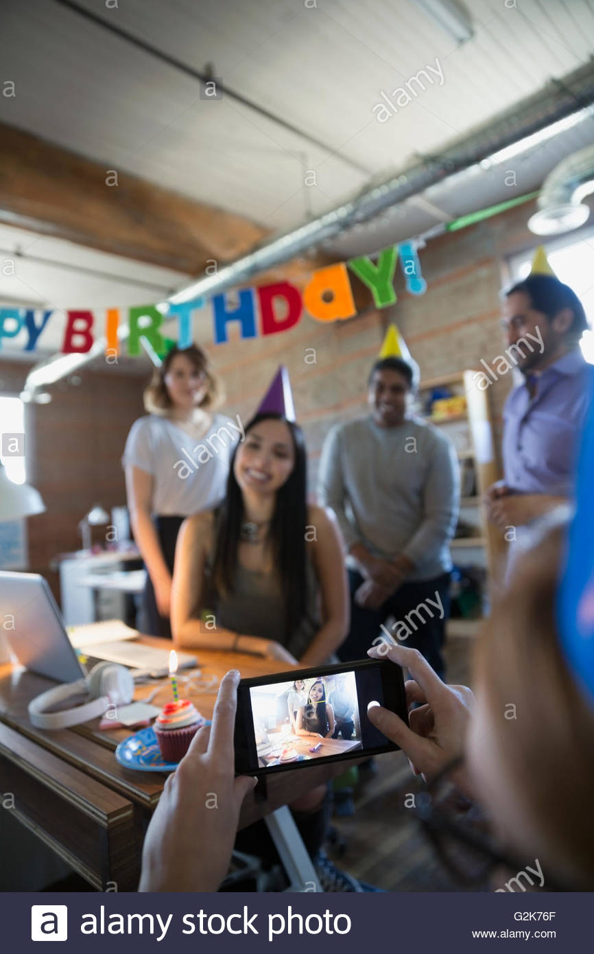 Collaboratore di fotografare imprenditrice godendo di festa di compleanno in ufficio Foto Stock