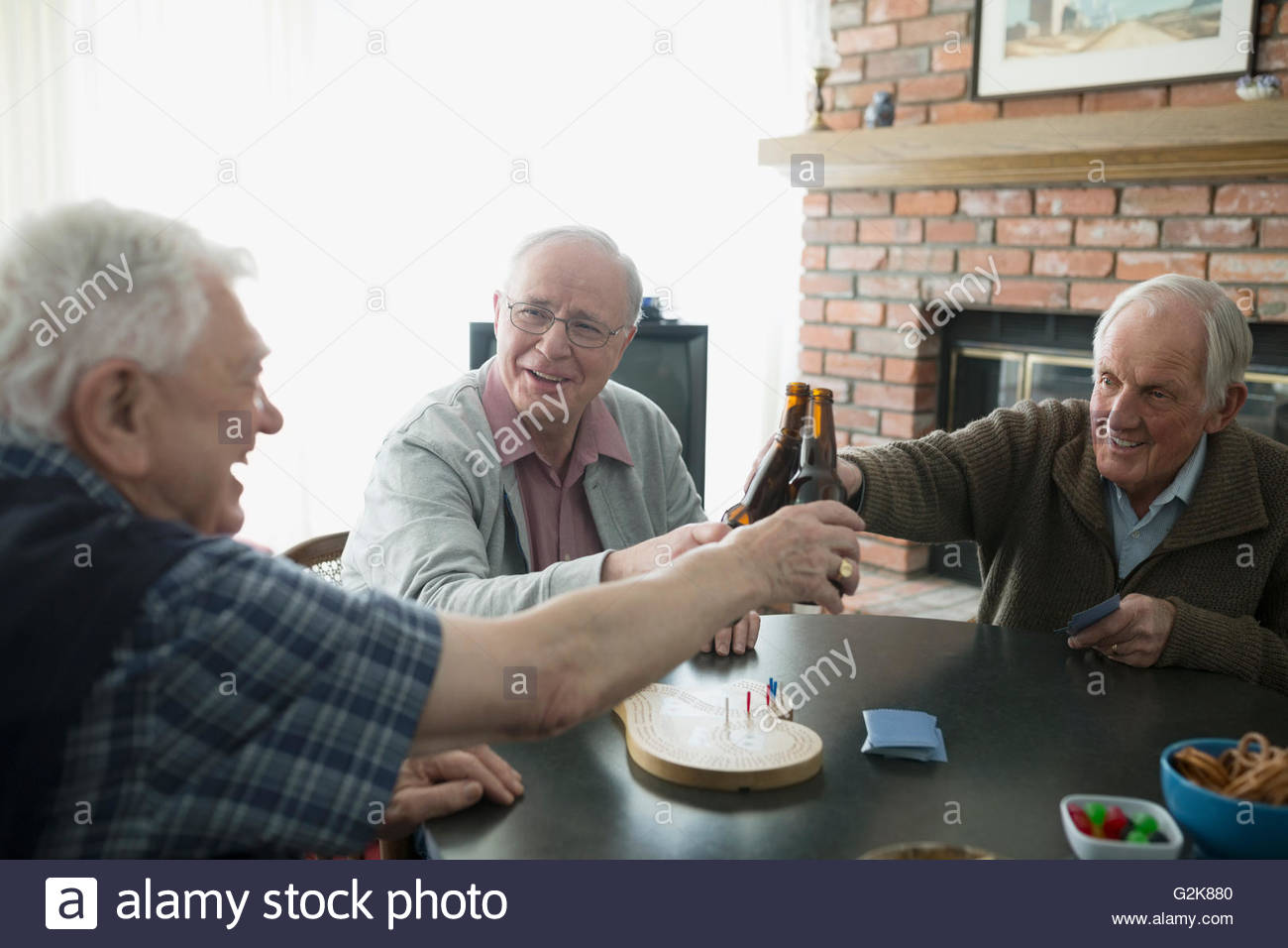 Alti uomini playing cribbage e tostatura di bottiglie di birra Foto Stock