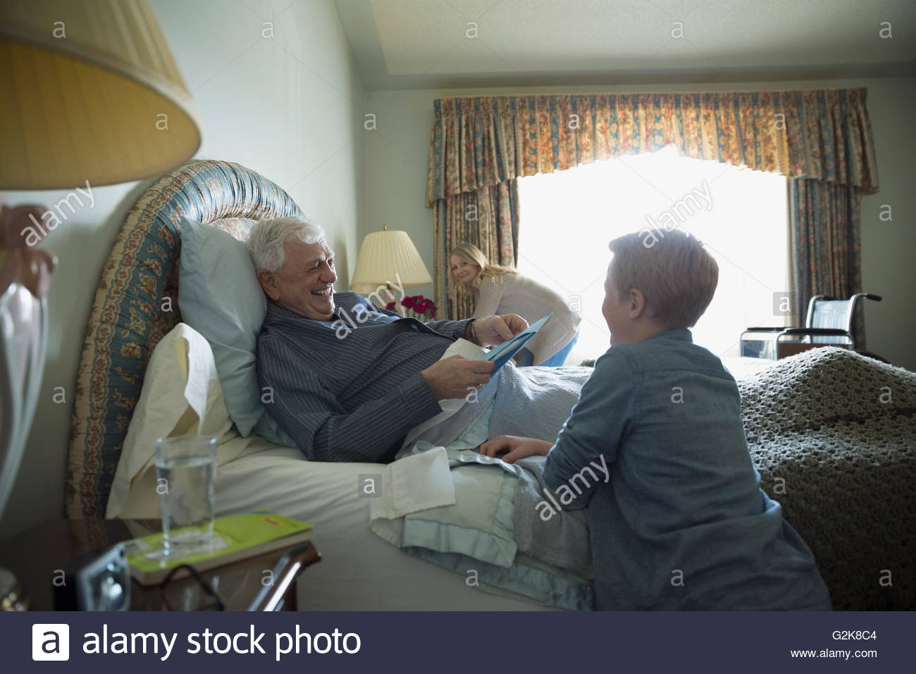 Nipote nonno in visita in appoggio a letto Foto Stock