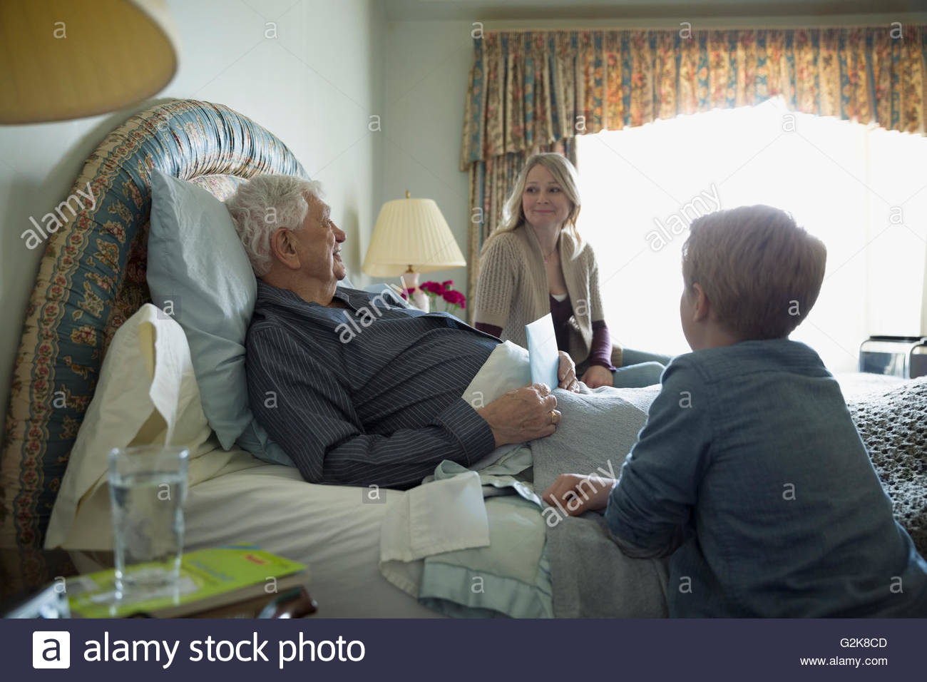 La figlia e la nipote nonno in visita in appoggio a letto Foto Stock