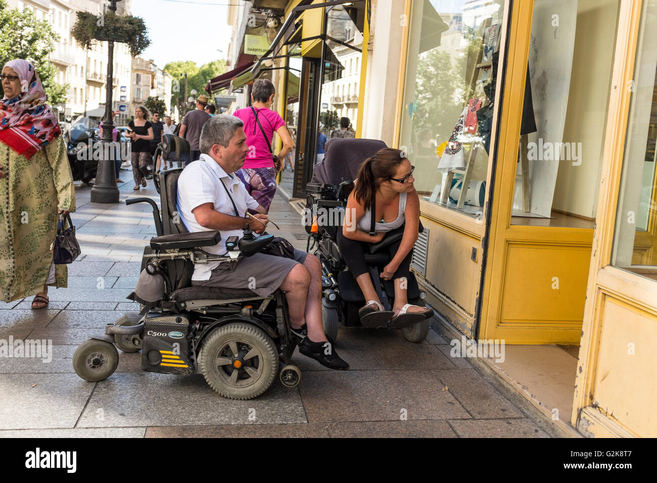 Due sedie a rotelle in attesa al di fuori di un negozio a causa di mancanza di accessibilità, Avignon, Francia Foto Stock