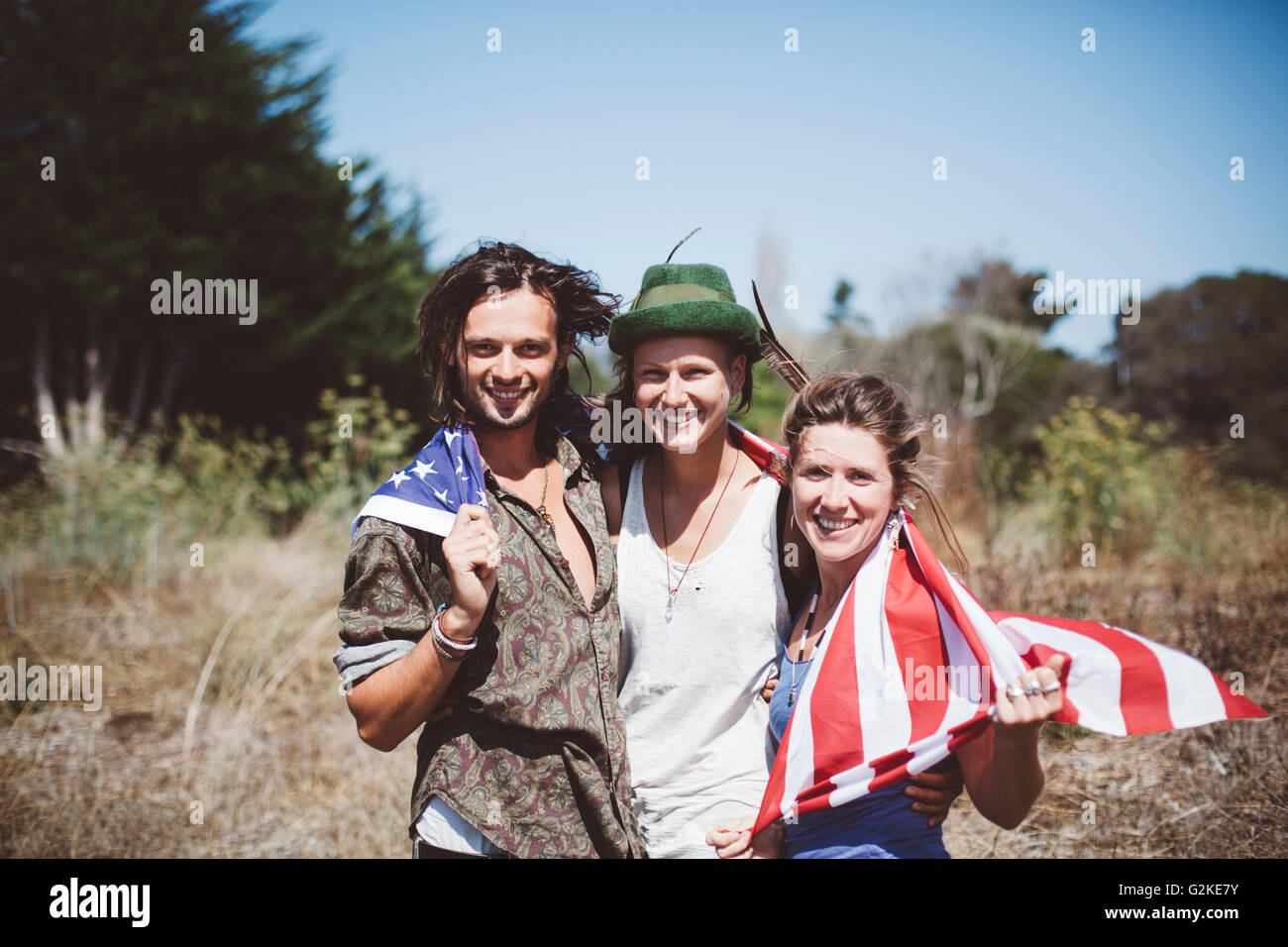 Ritratto di tre hippies sorridente con noi bandiera nella natura Foto Stock