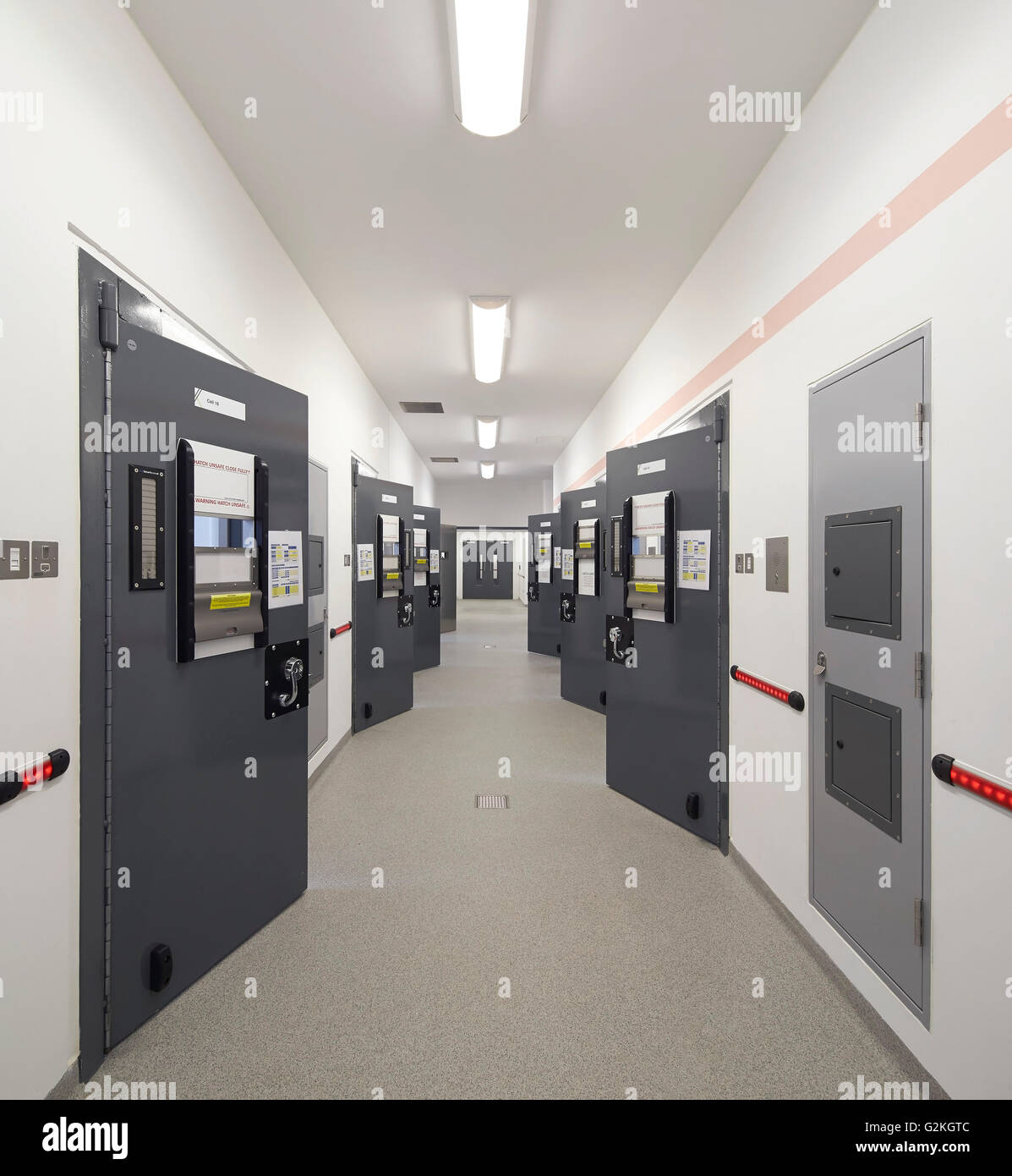 Corridoio con custodia porte di cella. Keynsham Custody Suite e di procedimenti giudiziari e di inchiesta Facility, Keynsham, Regno Unito. Architetto: Haverstock Associates LLP, 2014. Foto Stock