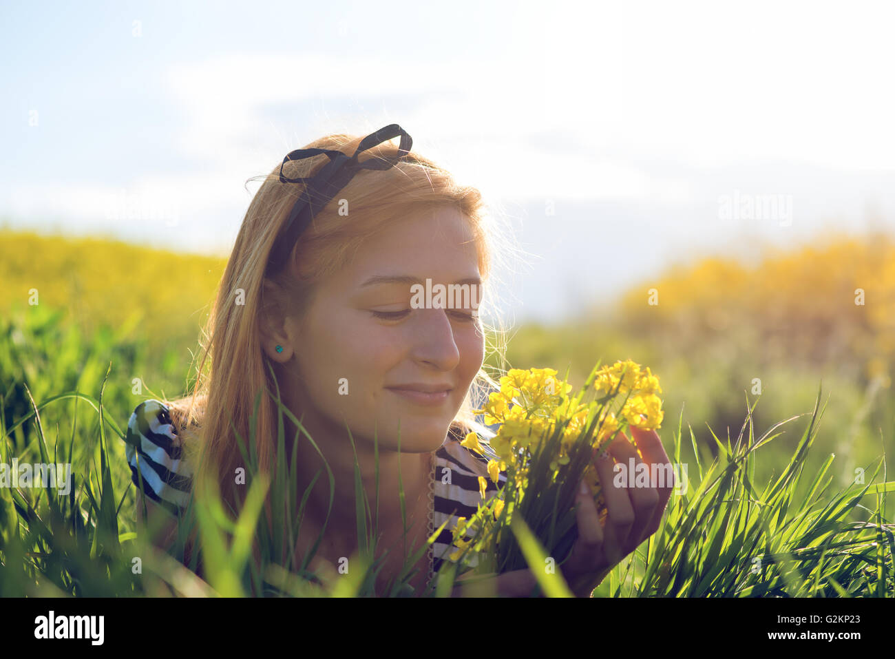 Carino giovane ragazza nel mezzo di un campo di fiori gialli Foto Stock