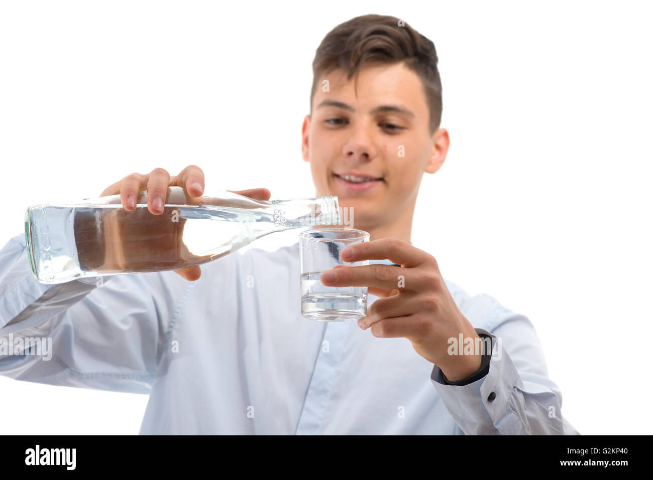 Adolescente cameriere versando acqua dalla bottiglia di vetro in un vetro isolato su bianco Foto Stock