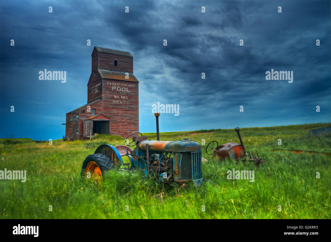 Elevatori della granella e i vecchi trattori in città fantasma Bents Saskatchewan Canada Foto Stock