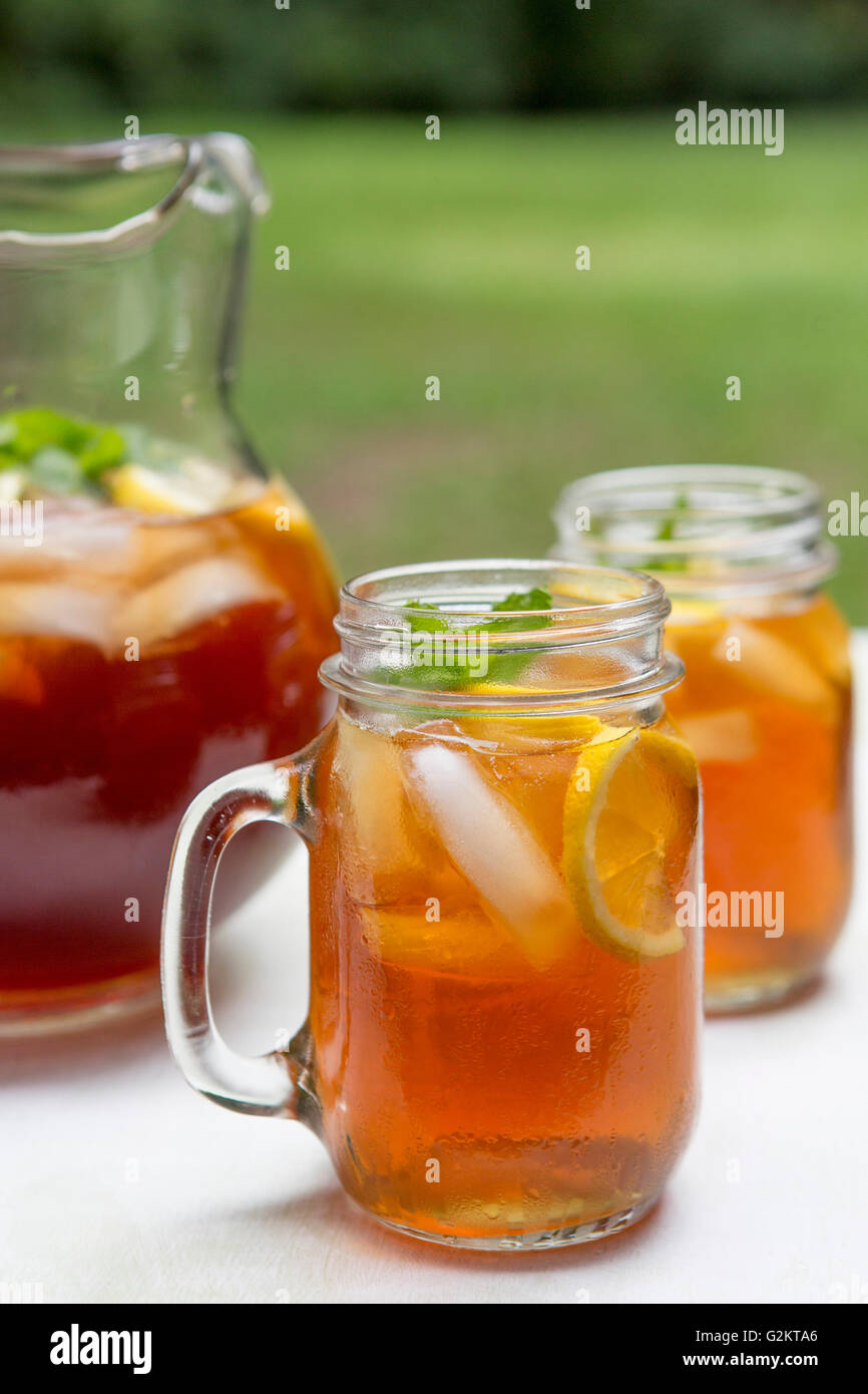 Tè freddo in brocca e tazze di vetro con limone e menta Foto Stock