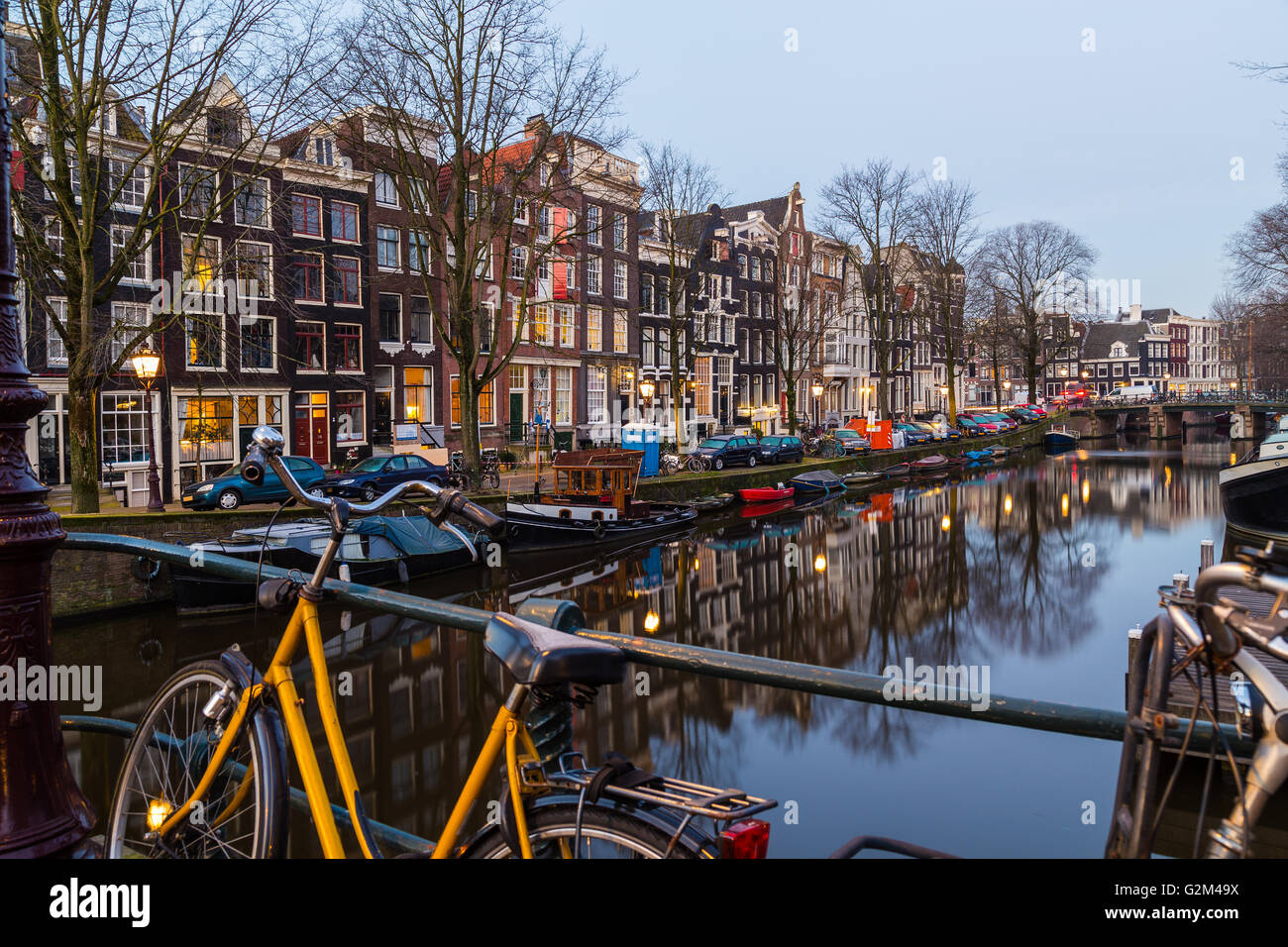 Biciclette, edifici e barche lungo i canali di Amsterdam all'alba. Foto Stock