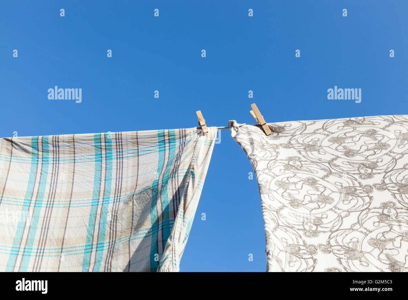 Asciugatura in una giornata di sole. Picchetti di legno azienda abbigliamento su una linea di lavaggio Foto Stock