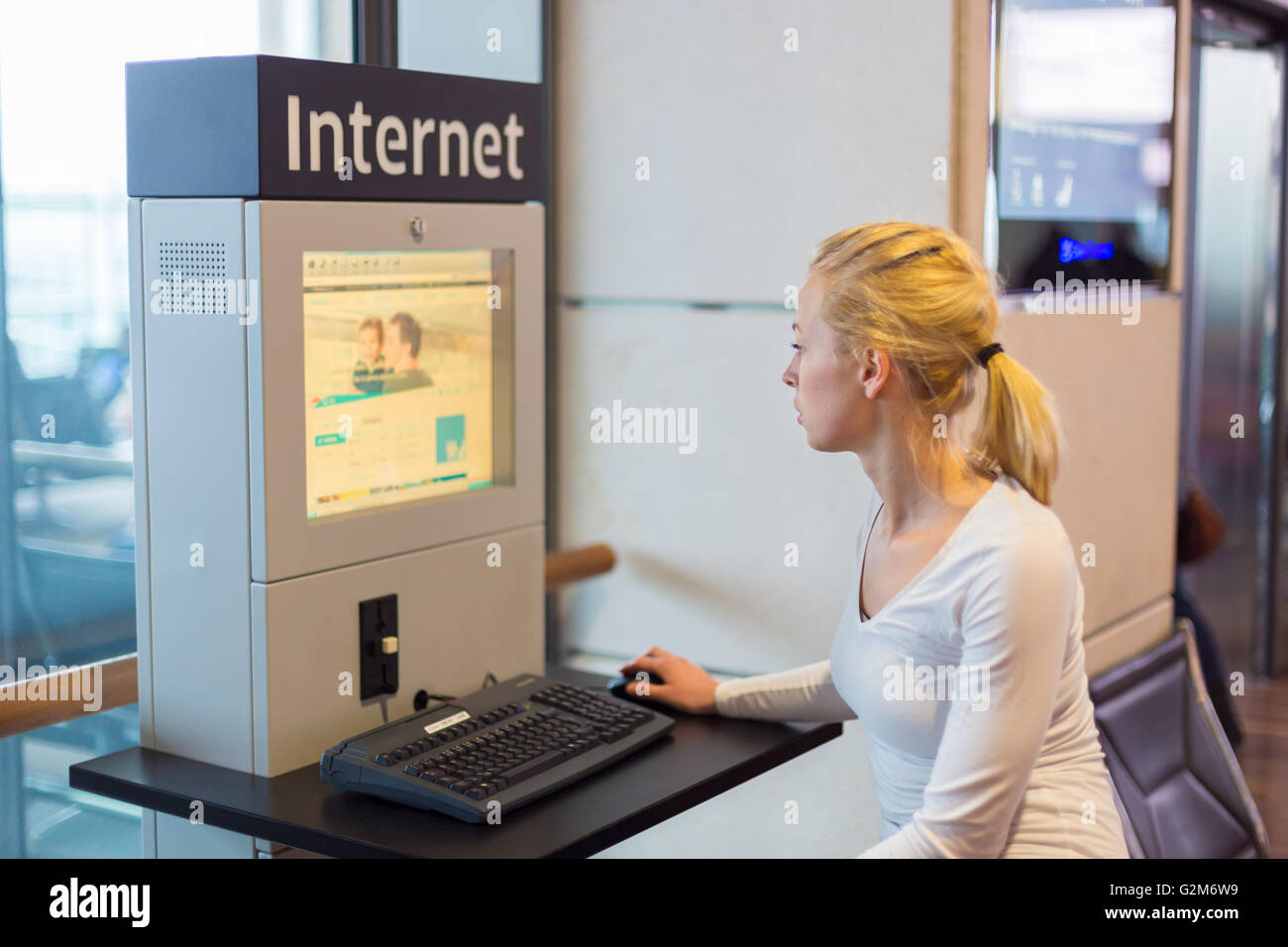 Donna accesso pubblico a internet point in aeroporto. Foto Stock