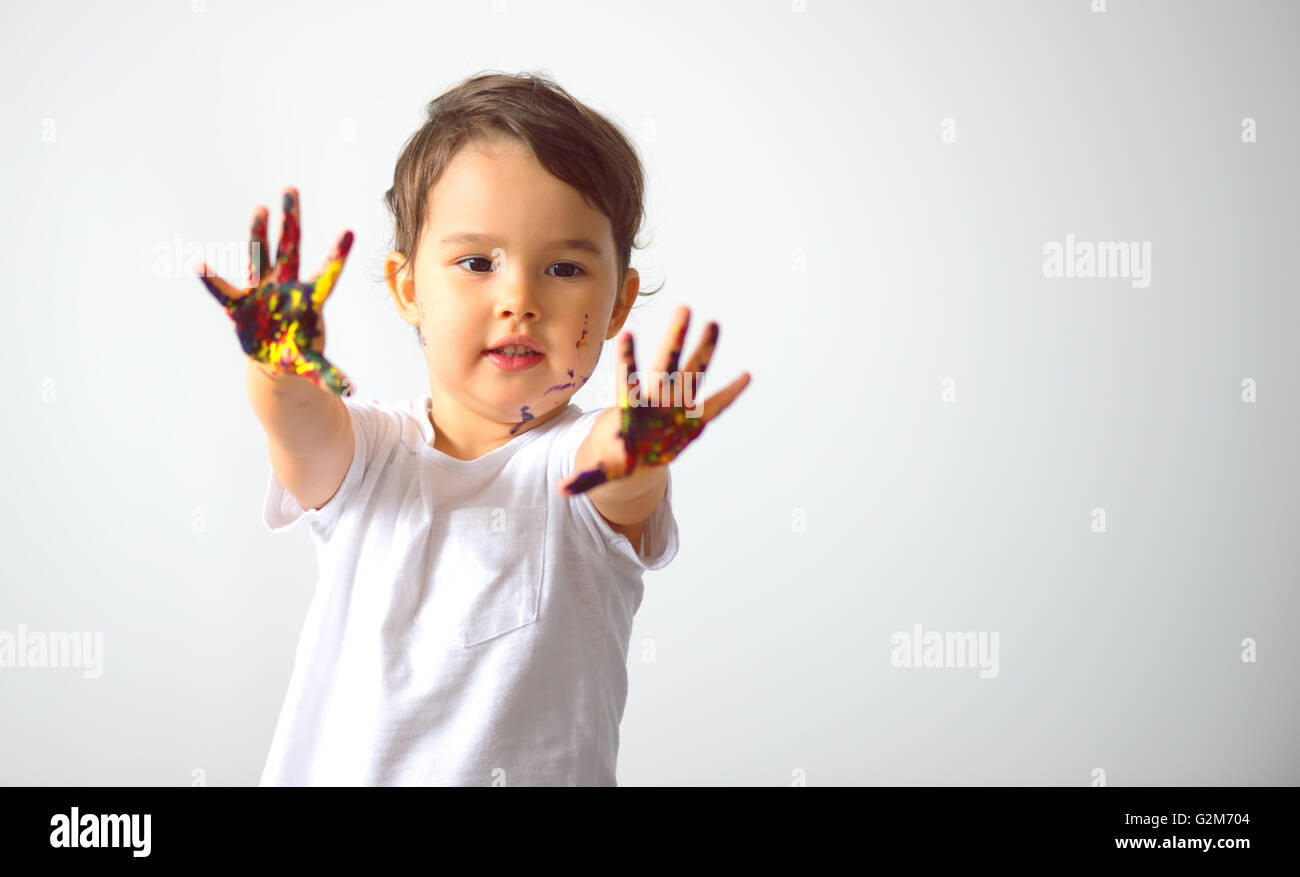 Ritratto di un simpatico bambina che mostra le sue mani dipinte in colori vivaci Foto Stock